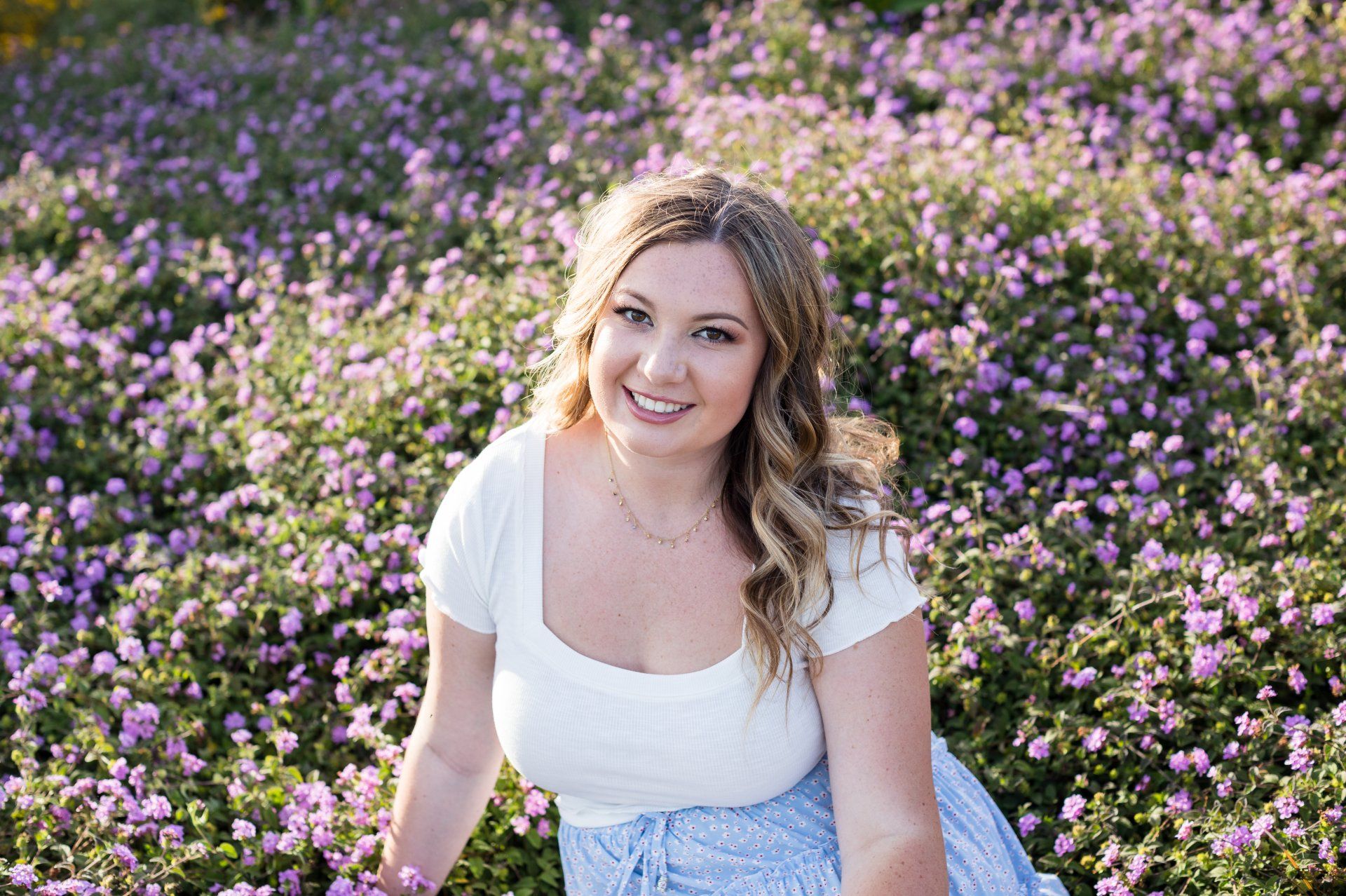 A woman is sitting in a field of purple flowers.