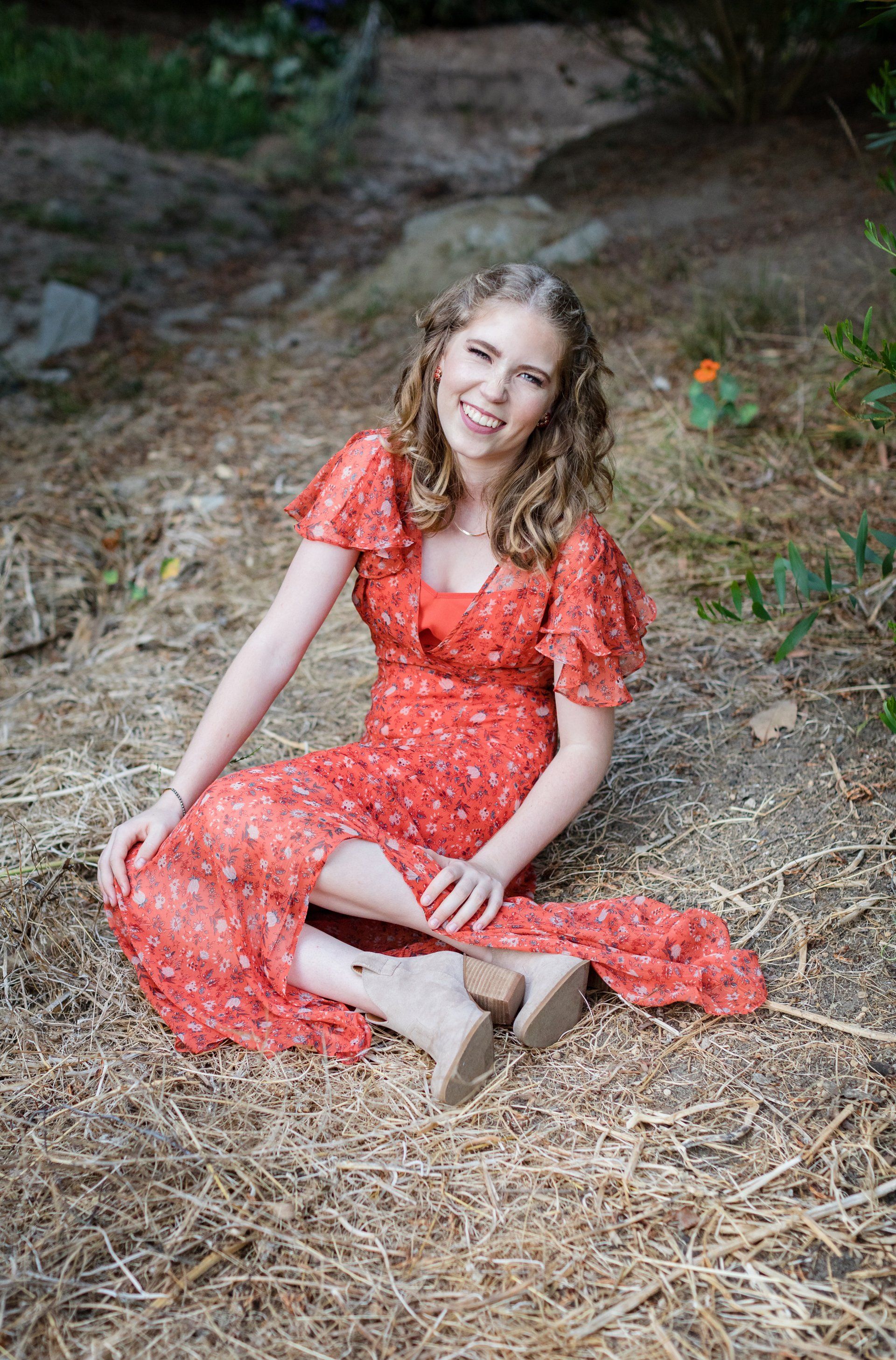 A woman in a red dress is sitting on the ground.