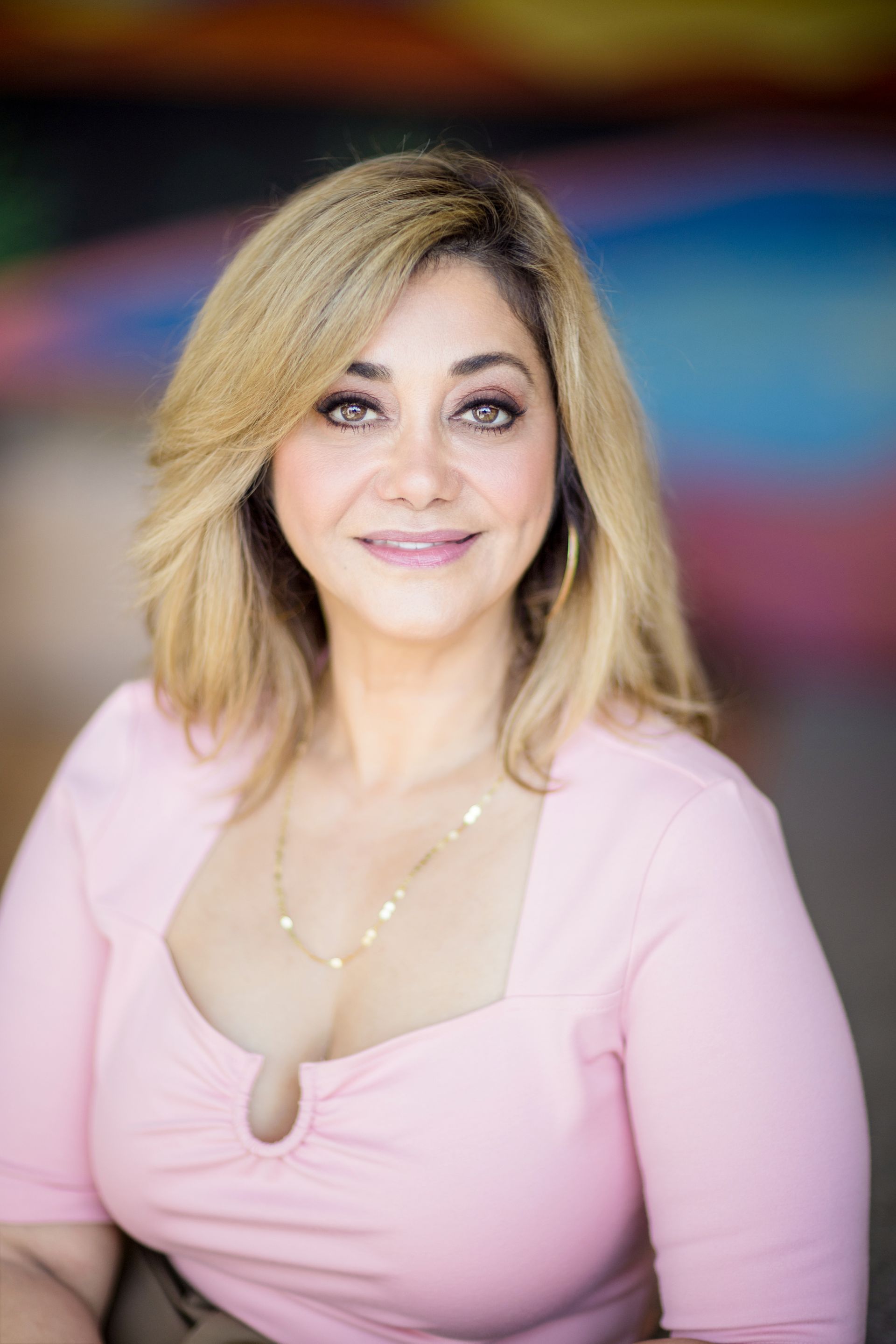A woman in a pink shirt is smiling for the camera.