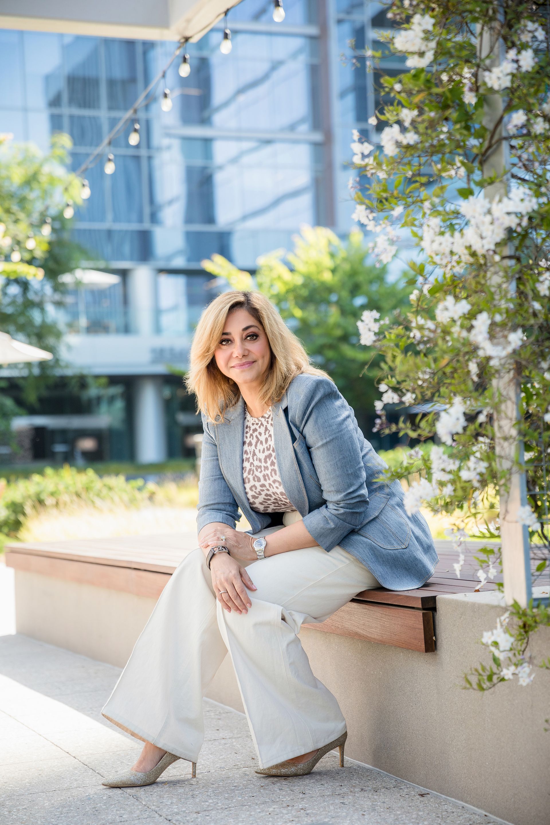 A woman is sitting on a bench in front of a building.