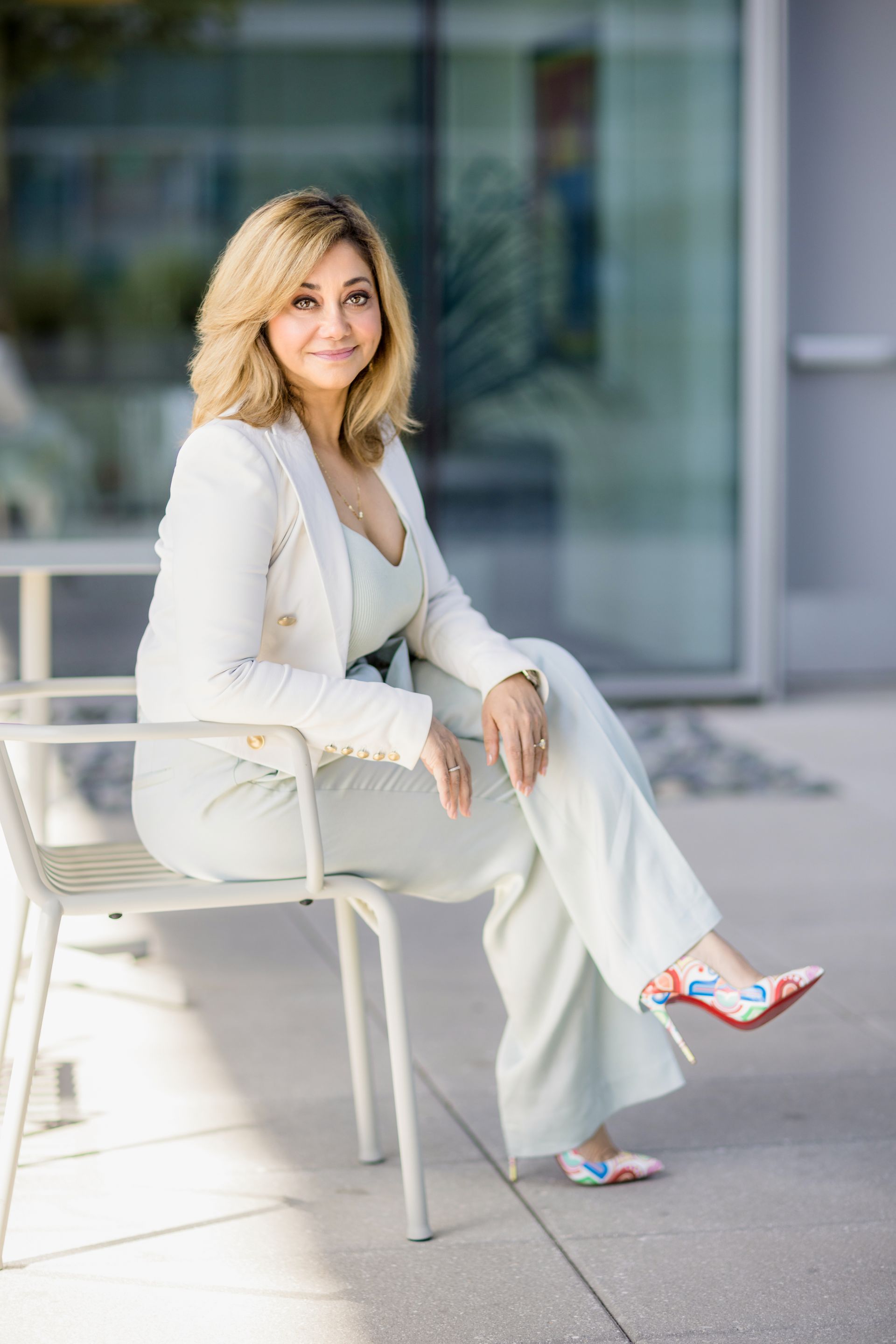 A woman in a white suit is sitting on a chair.