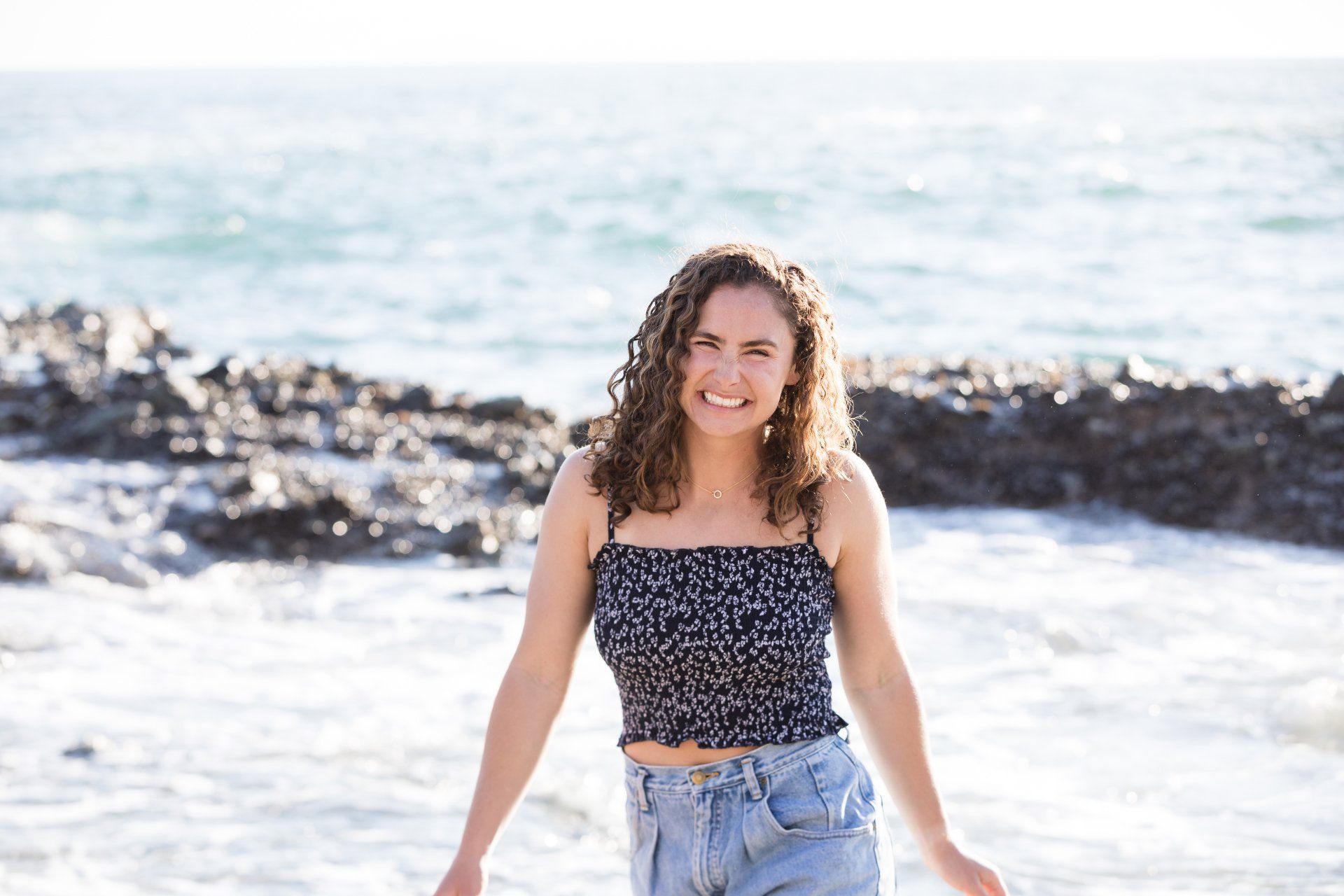 A young woman is standing on a beach near the ocean.