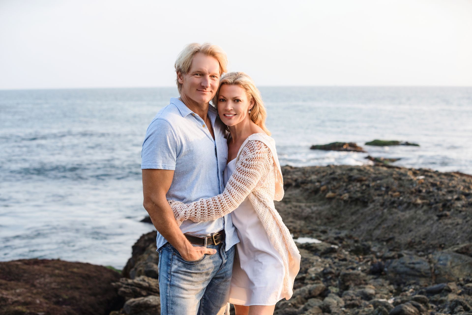 A man and a woman are posing for a picture on the beach in Laguna Beach.
