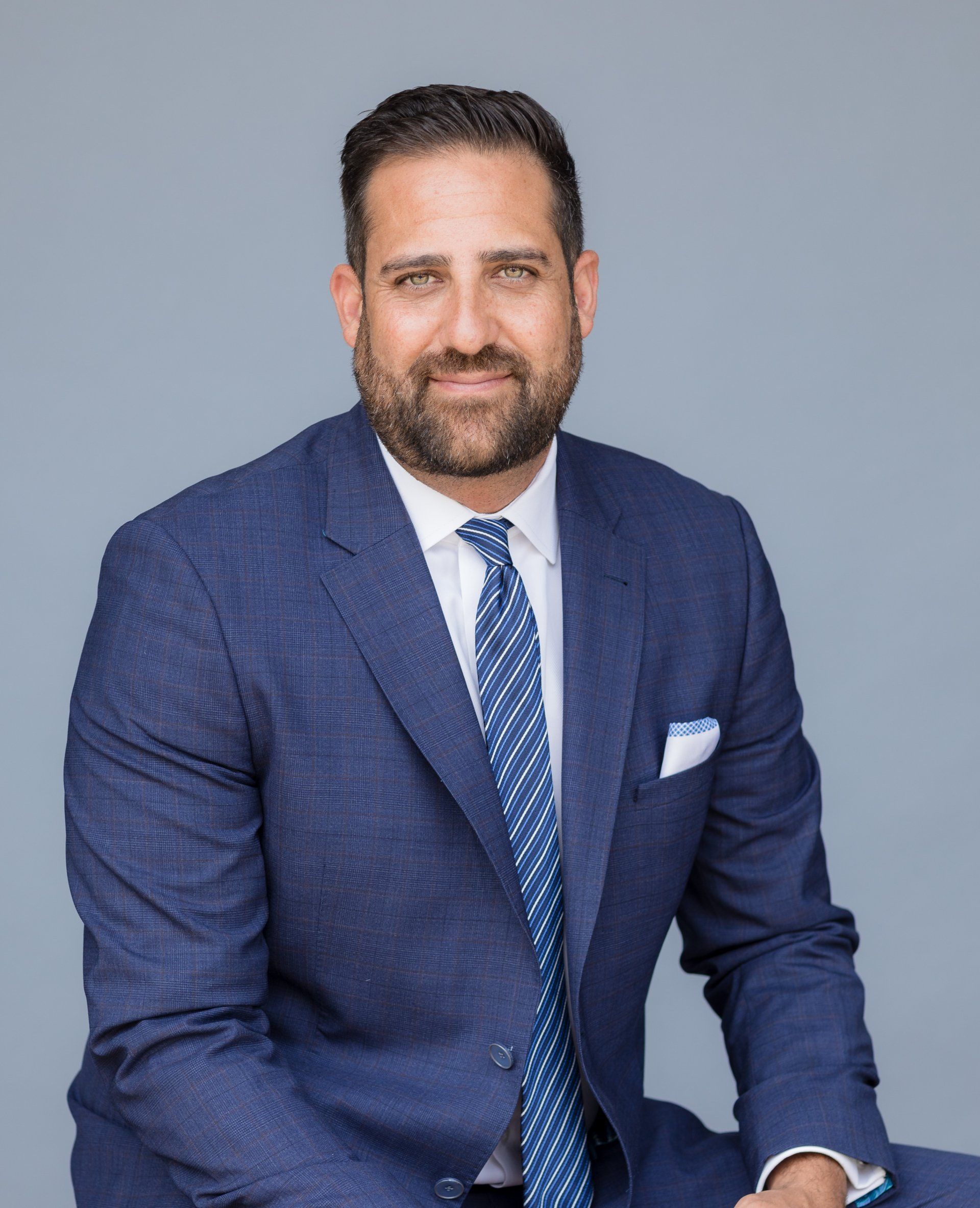 A man in a blue suit and tie is sitting down.