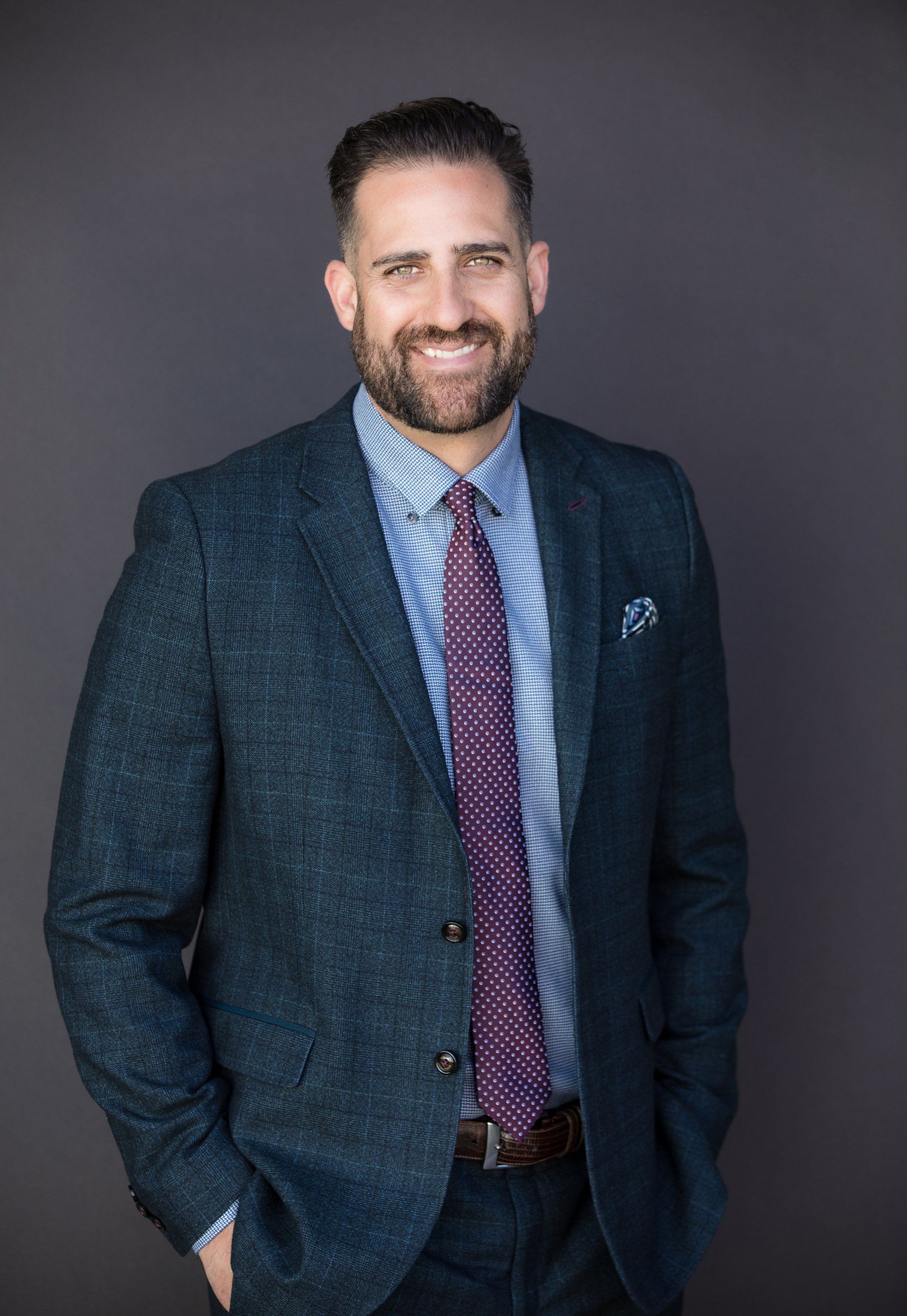 A man in a suit and tie is standing with his hands in his pockets.