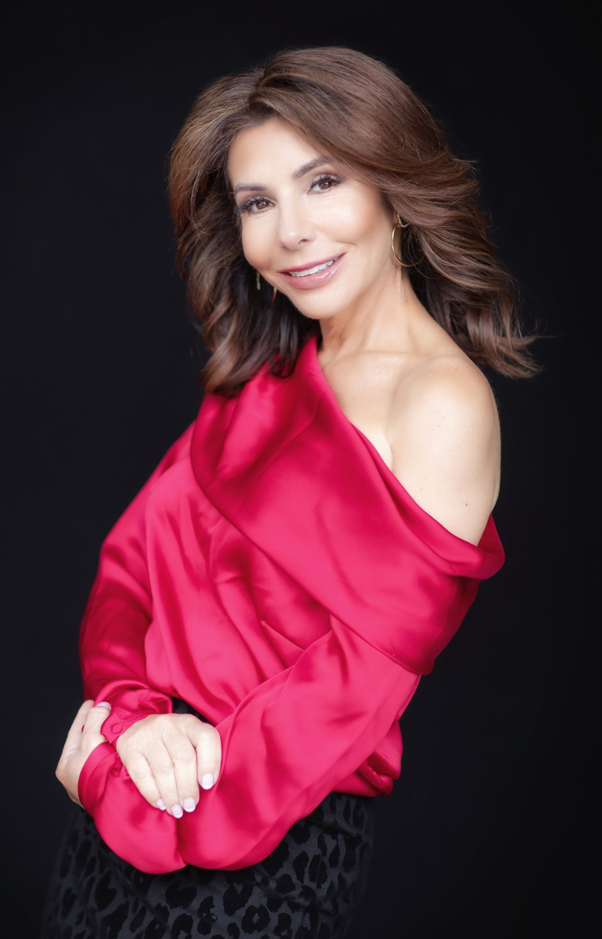 A woman is wearing a red off the shoulder top.