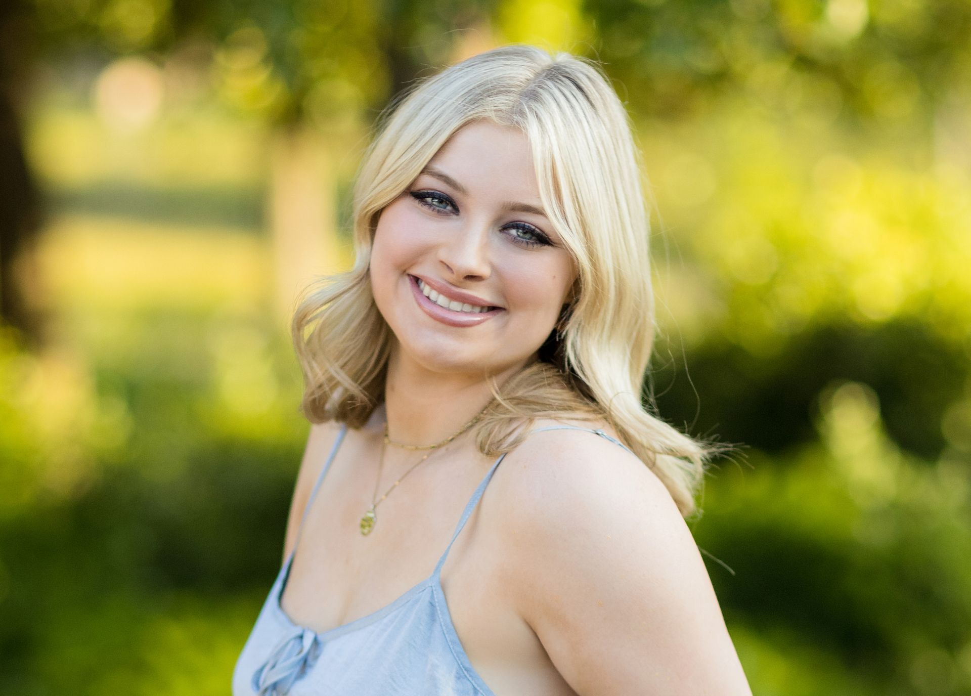 A young woman is smiling for the camera in a park.
