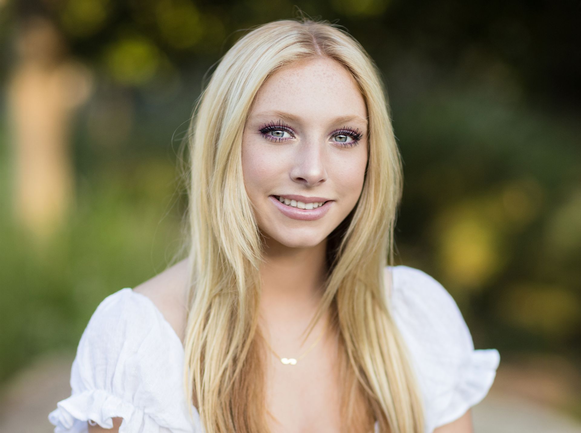 The woman is wearing a white shirt and smiling for the camera.