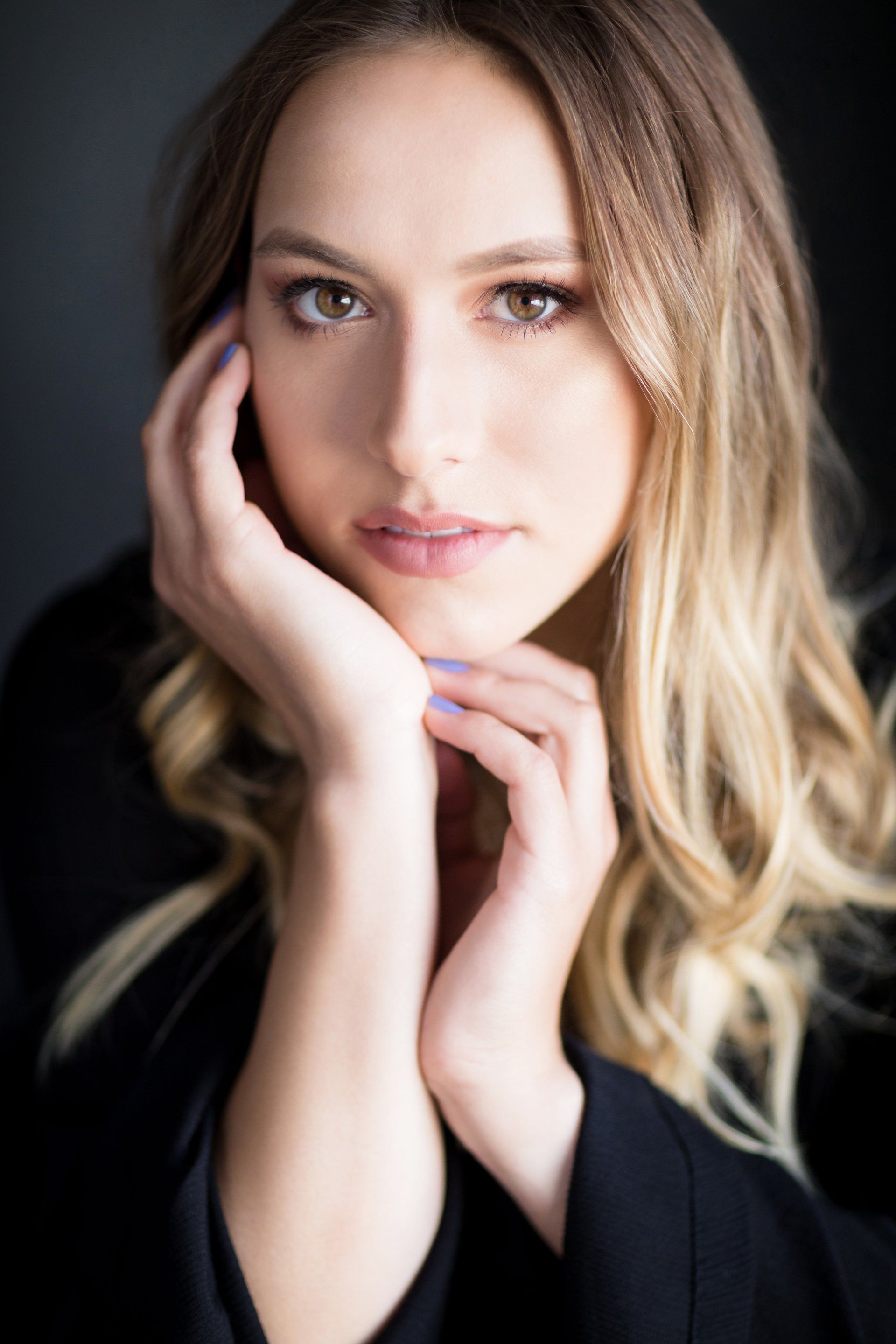 A close up of a woman 's face with her hand on her chin.