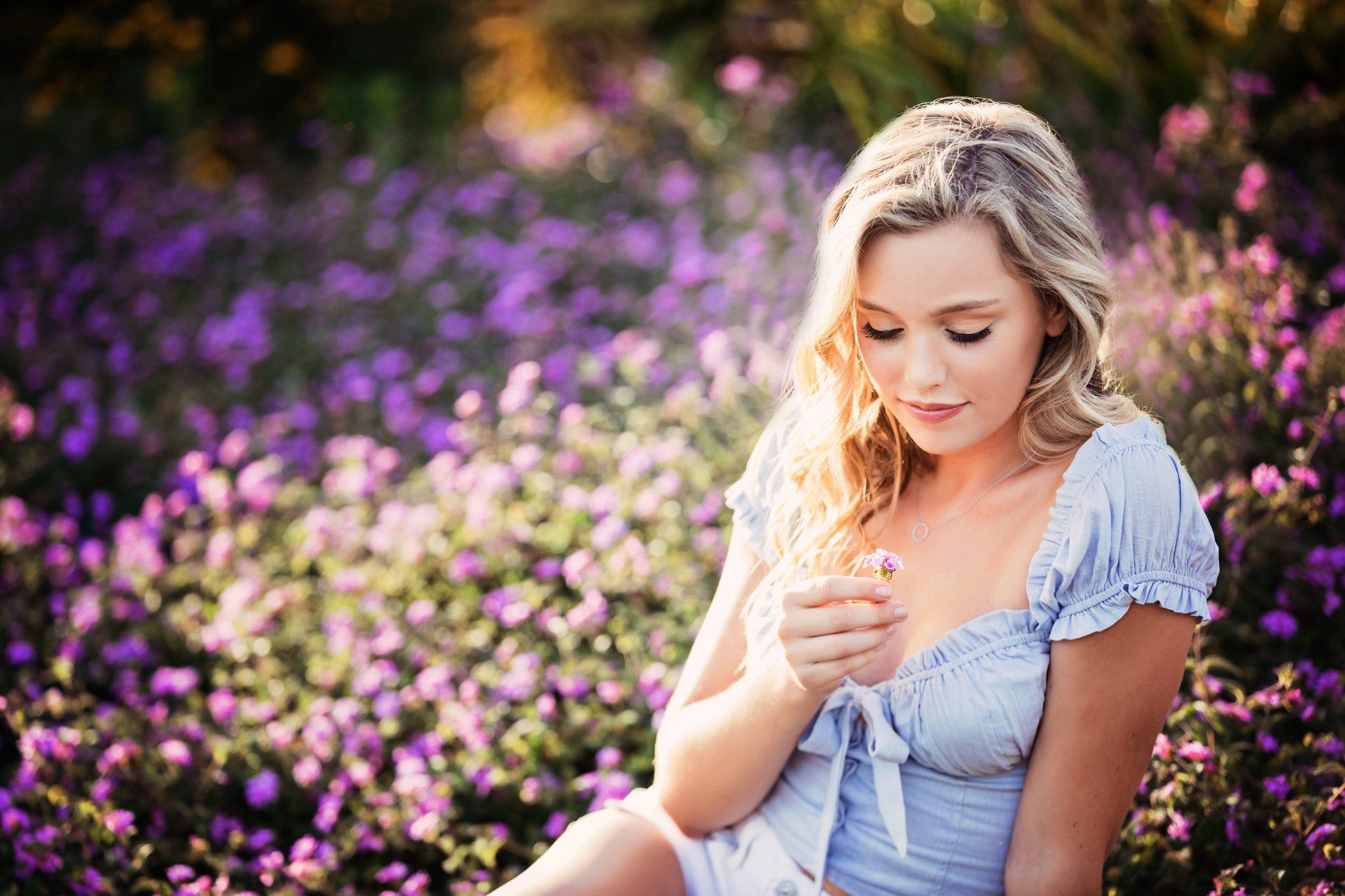 A woman is sitting in a field of purple flowers.
