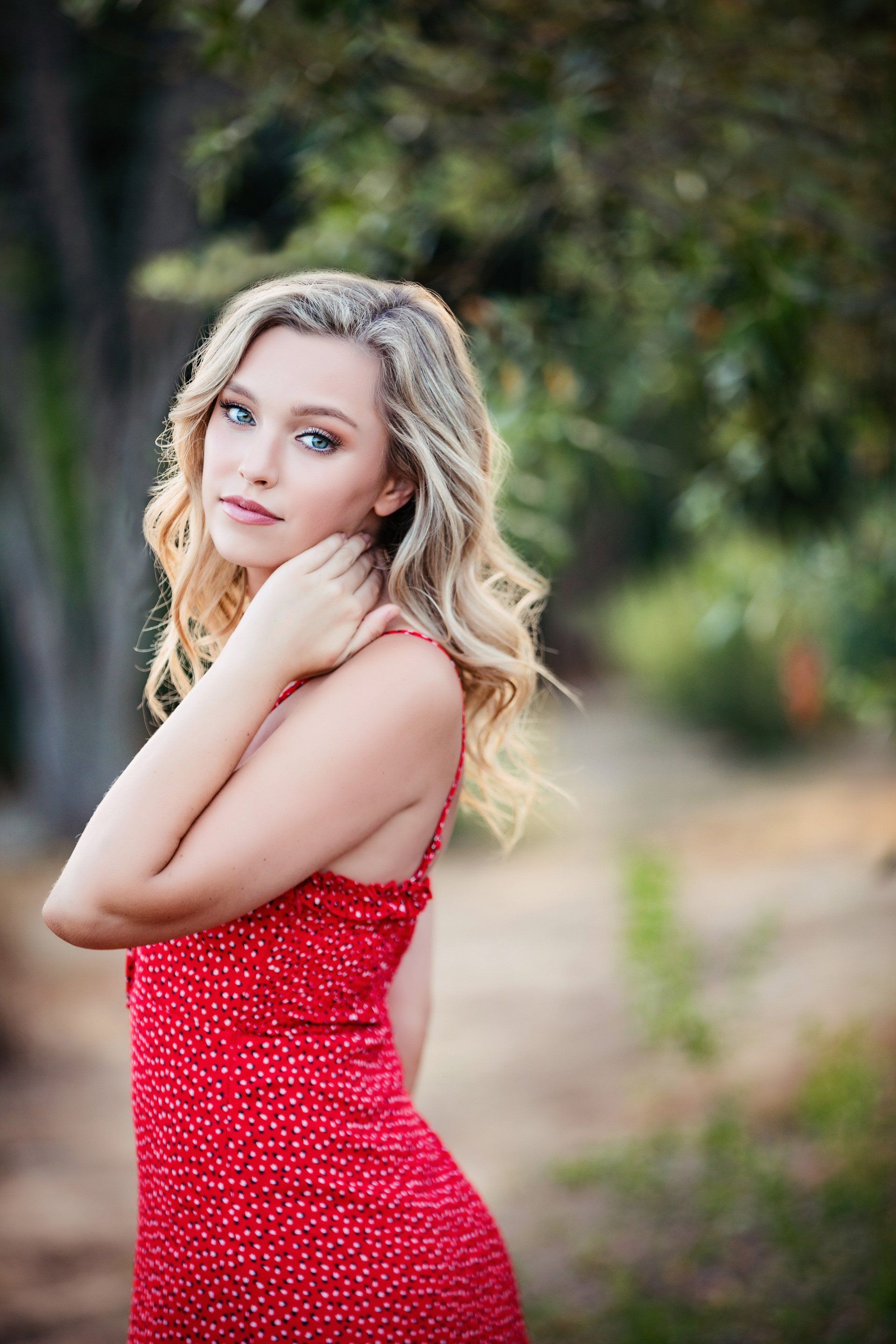 A woman in a red dress is standing in the woods.
