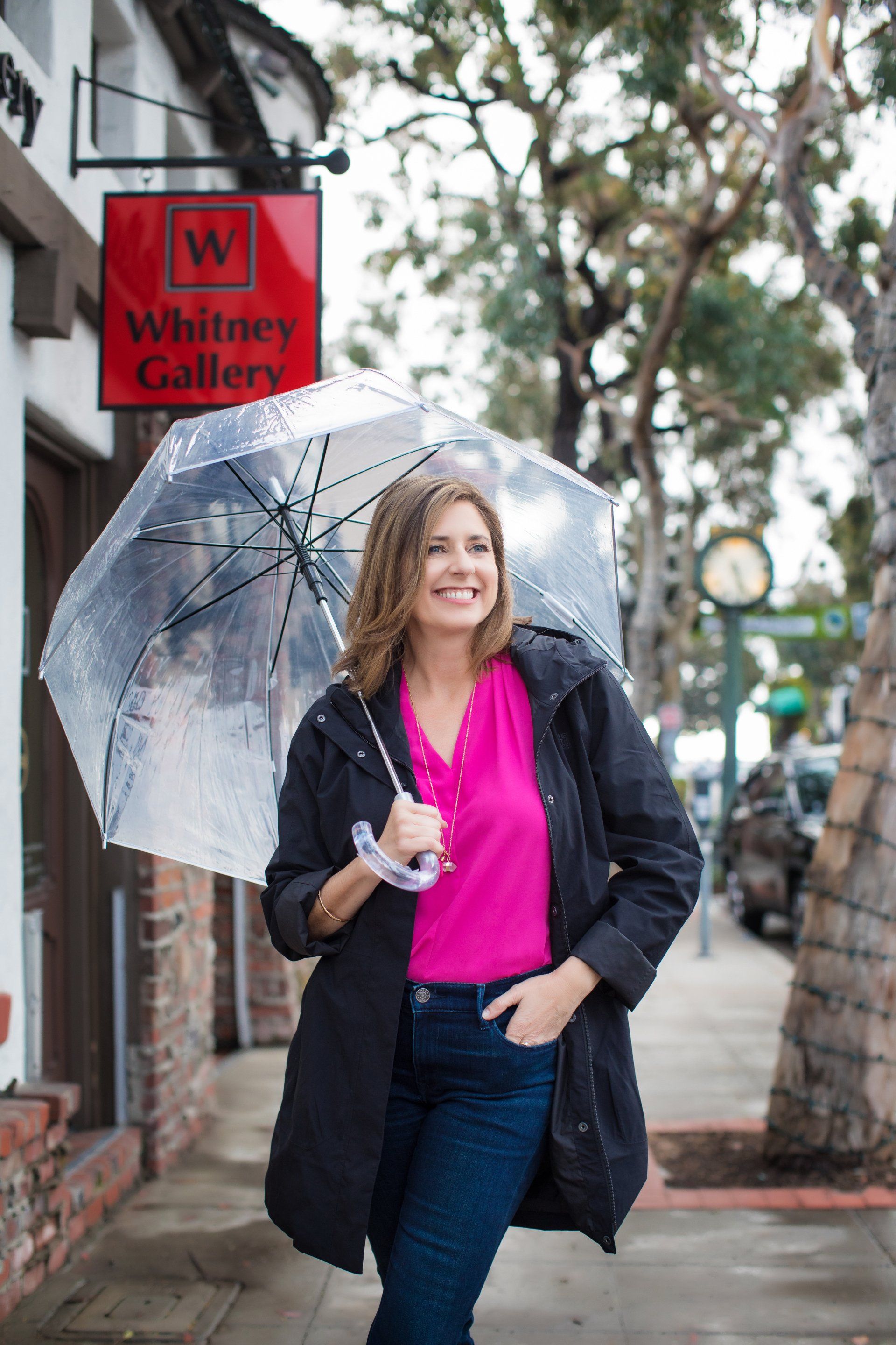 A woman is holding an umbrella on a sidewalk in front of a building.