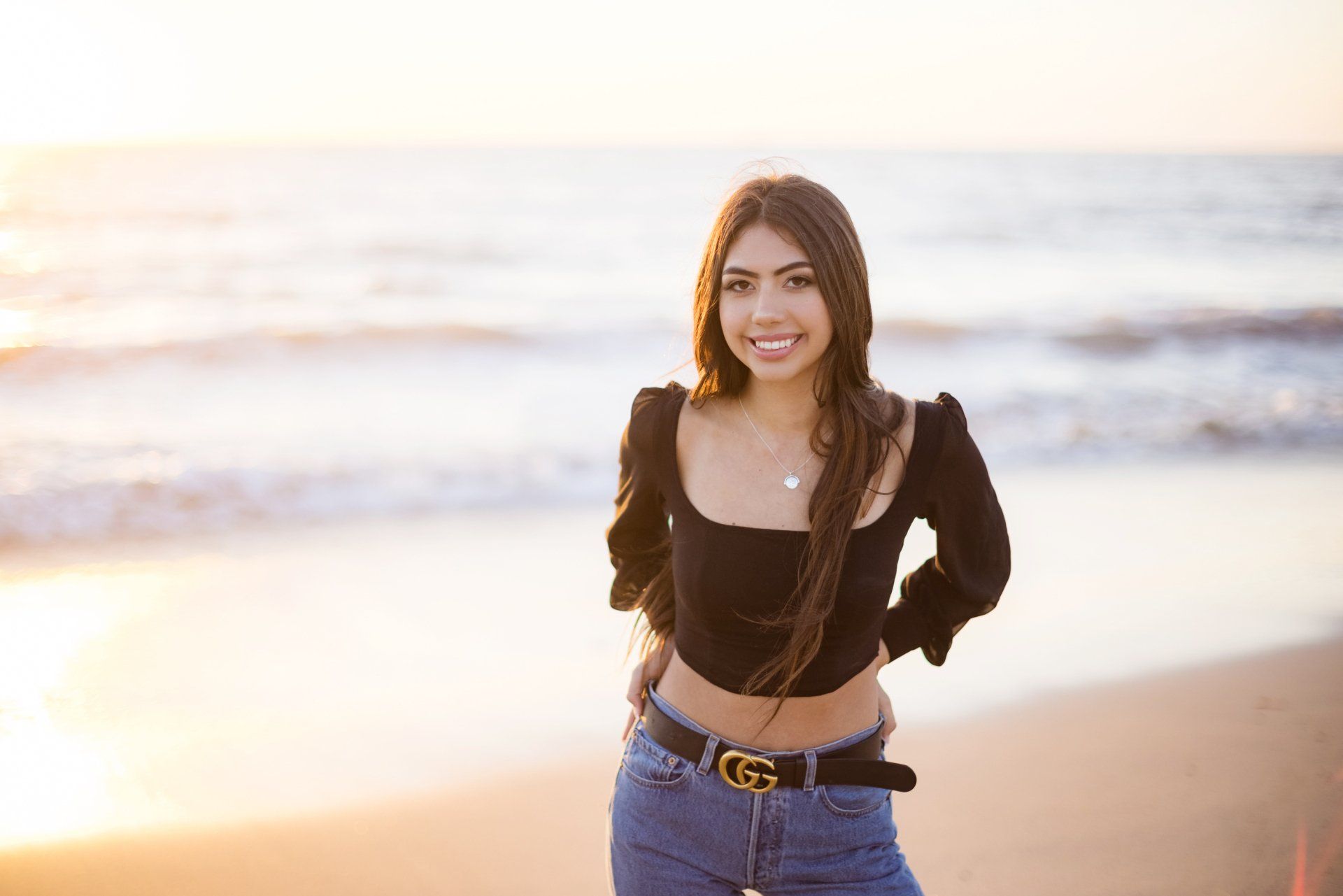 A woman is standing on a beach with her hands on her hips.