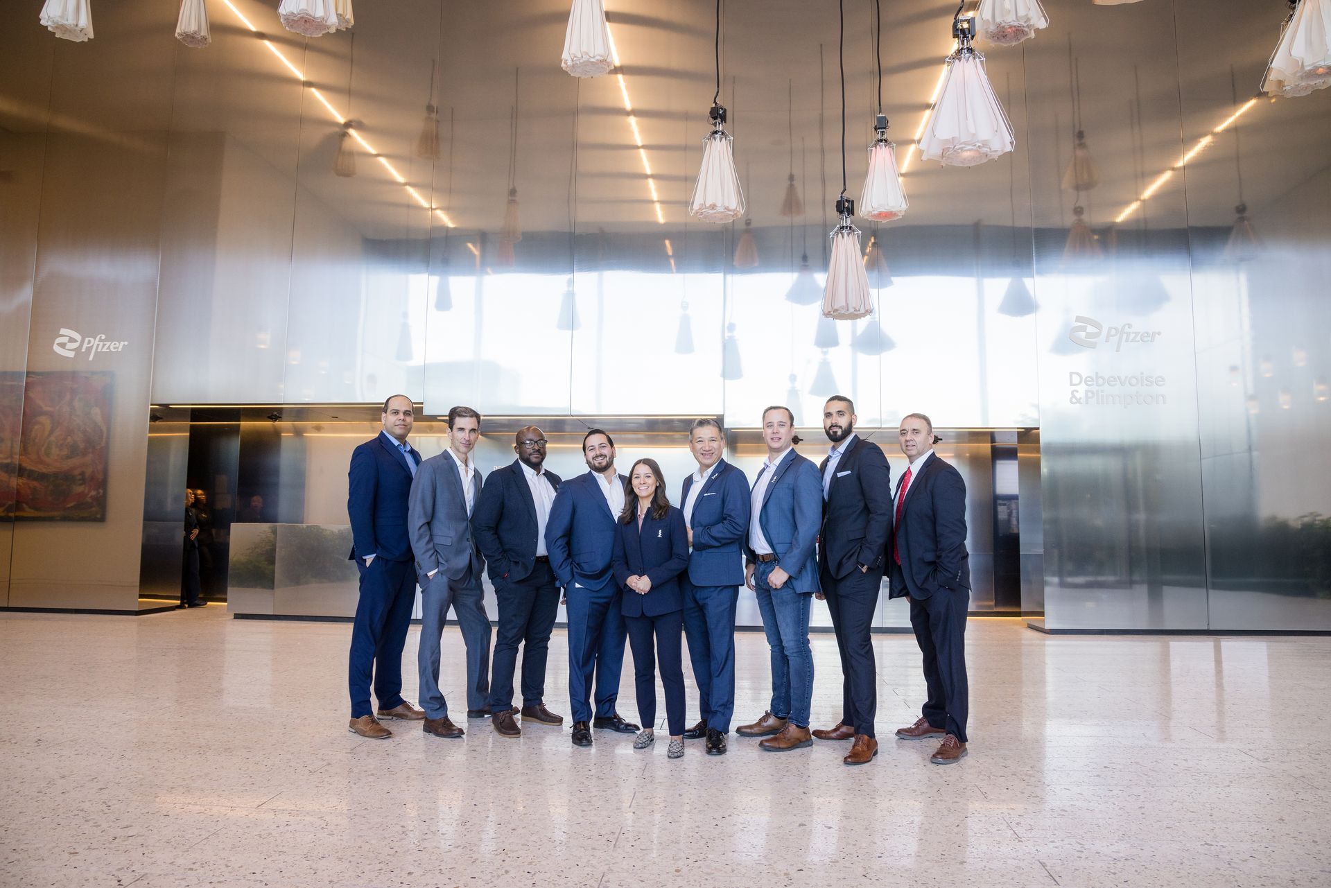 A group of people in suits are posing for a picture in a lobby.