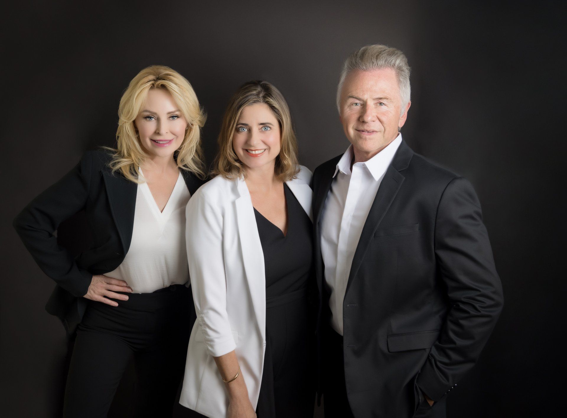 A man and two women are posing for a picture together.