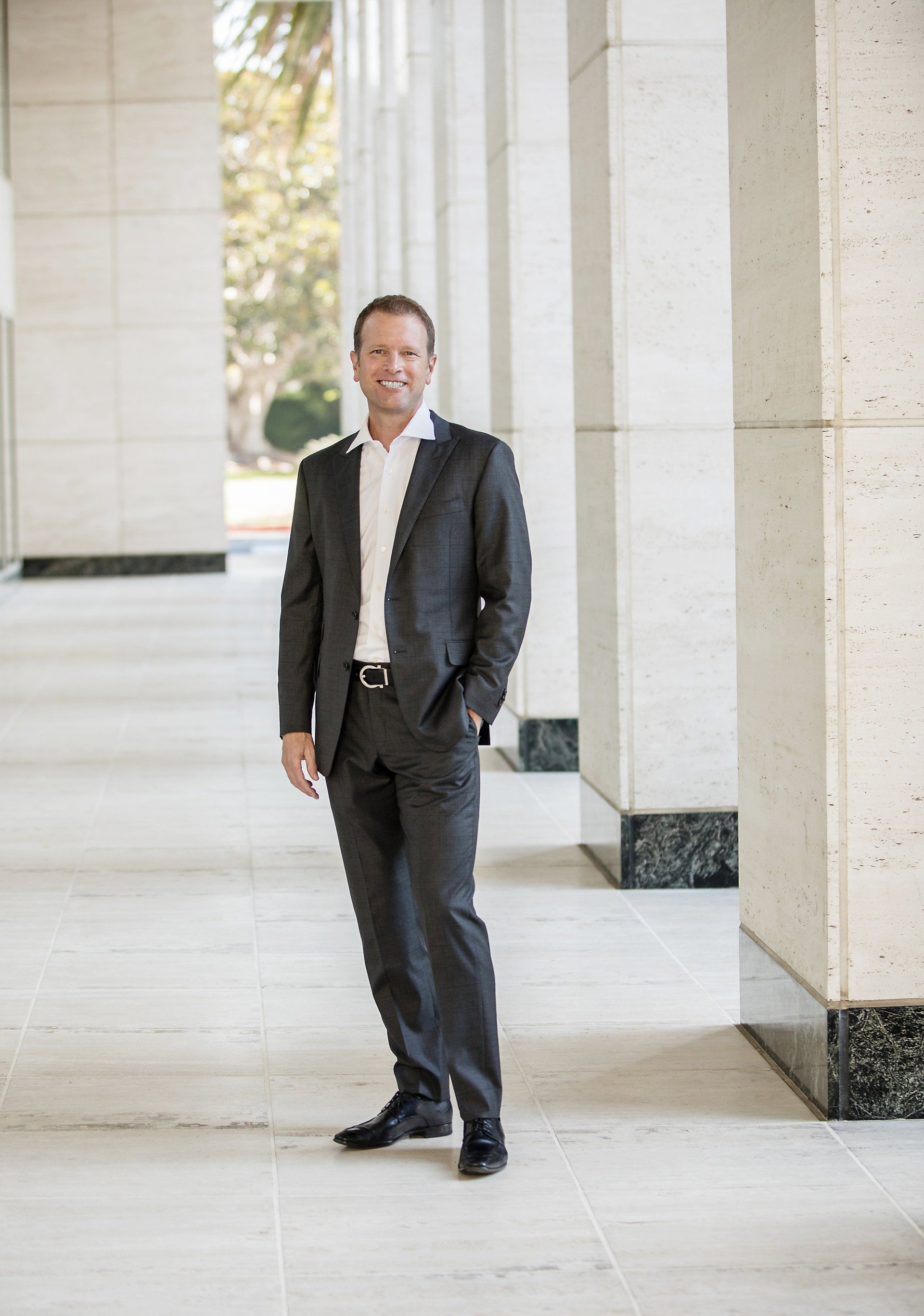 A man in a suit is standing in a hallway with his hands in his pockets.