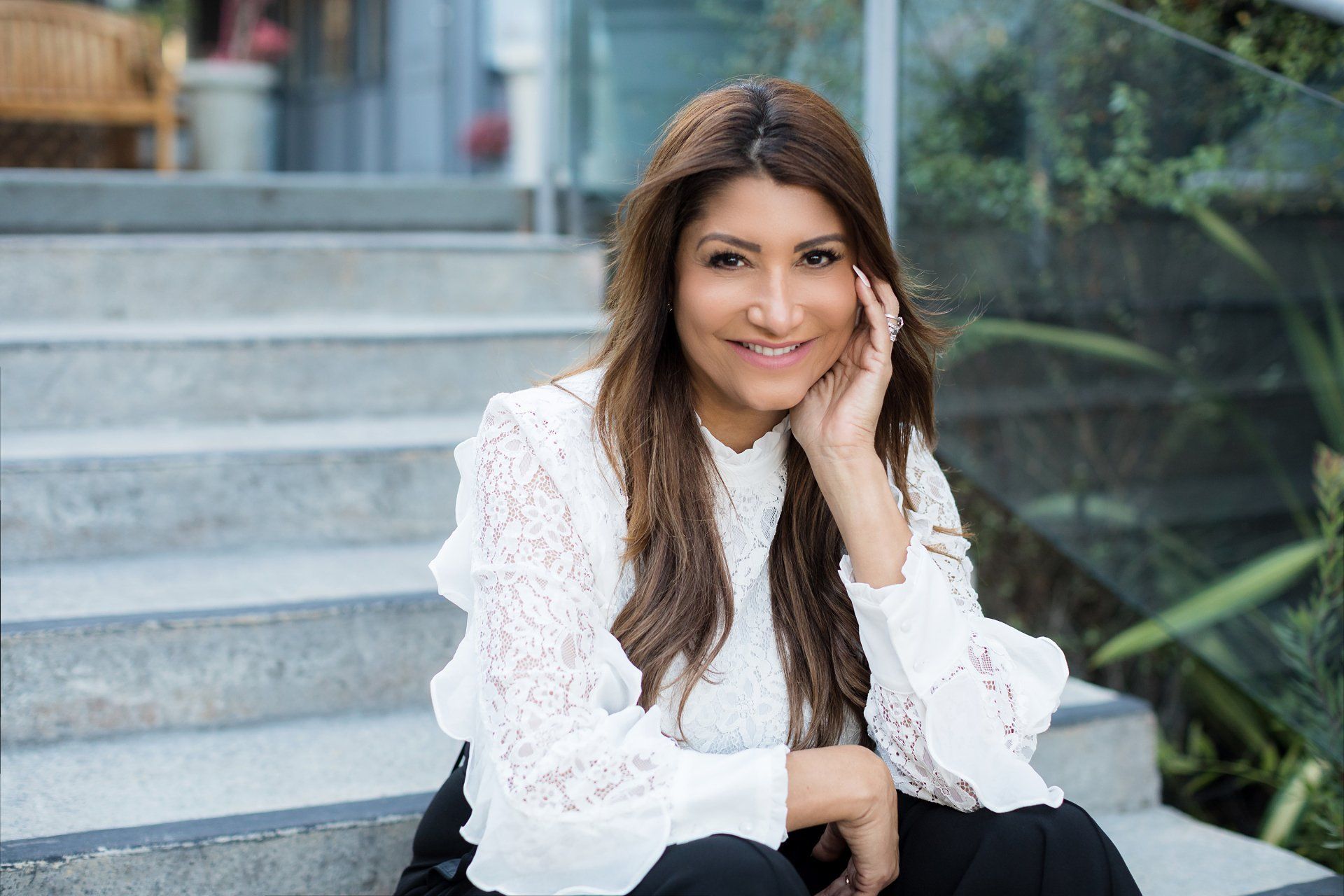 A woman is sitting on a set of stairs with her hand on her face.