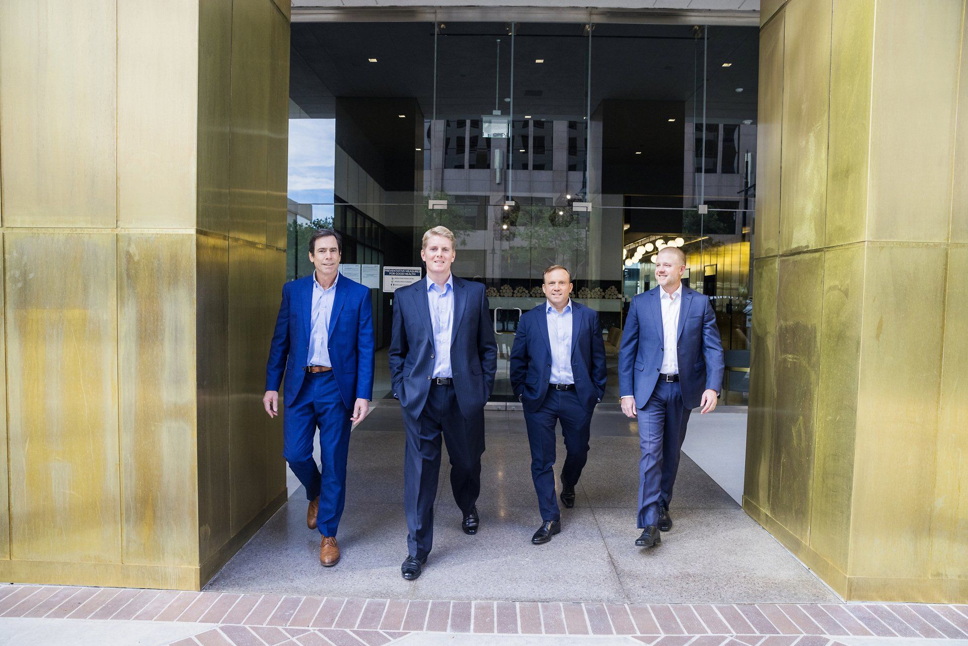 A group of men in suits are walking in front of a building.