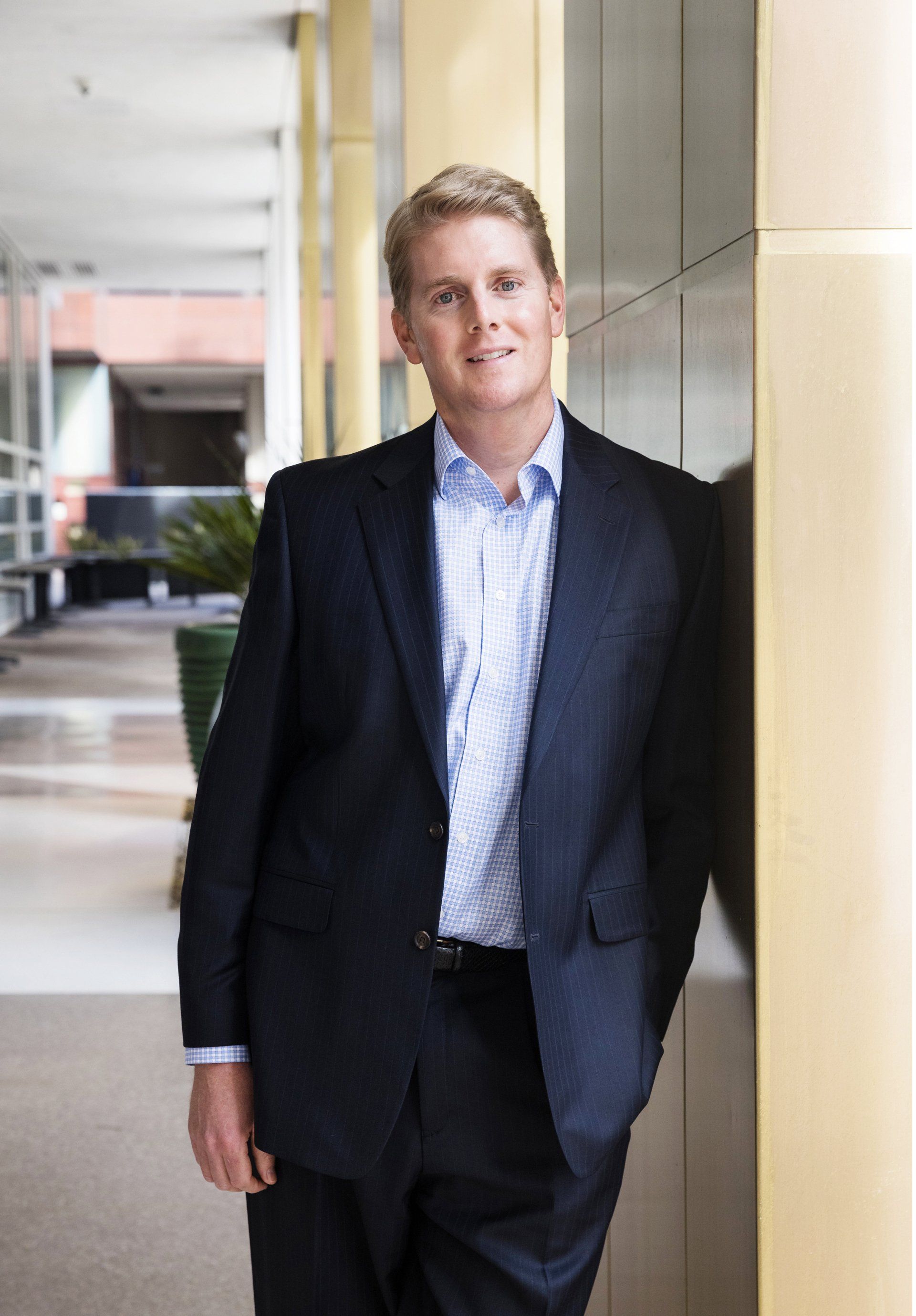 A man in a suit is leaning against a wall