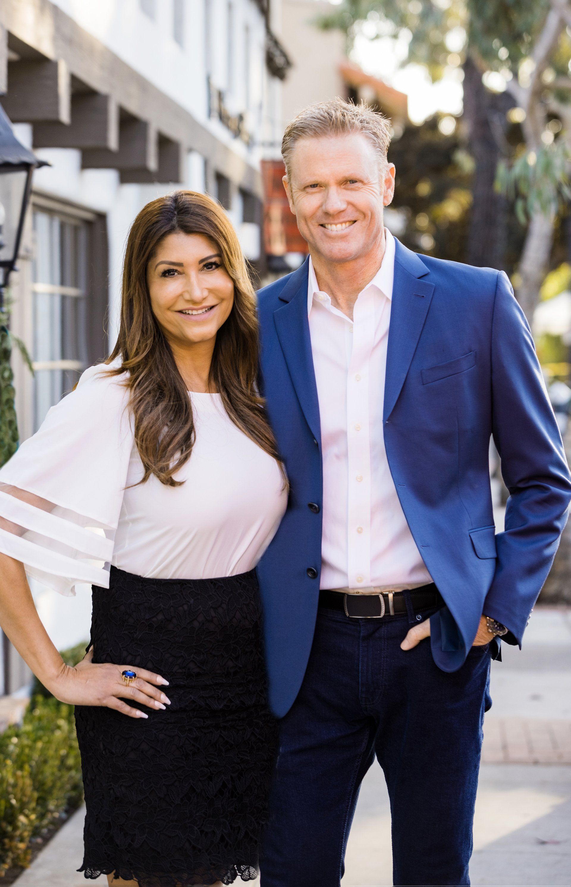 A man and a woman are standing next to each other on a sidewalk.