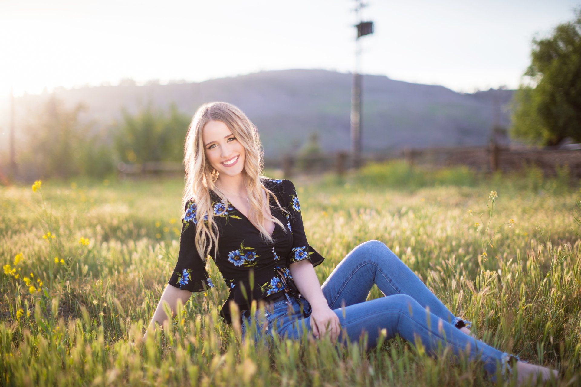 A woman is sitting on the grass in a field.