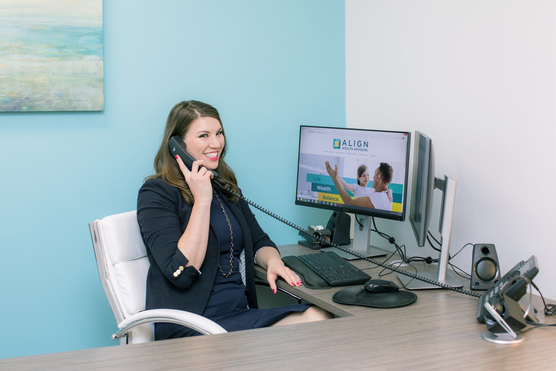 A woman is sitting at a desk talking on a phone.