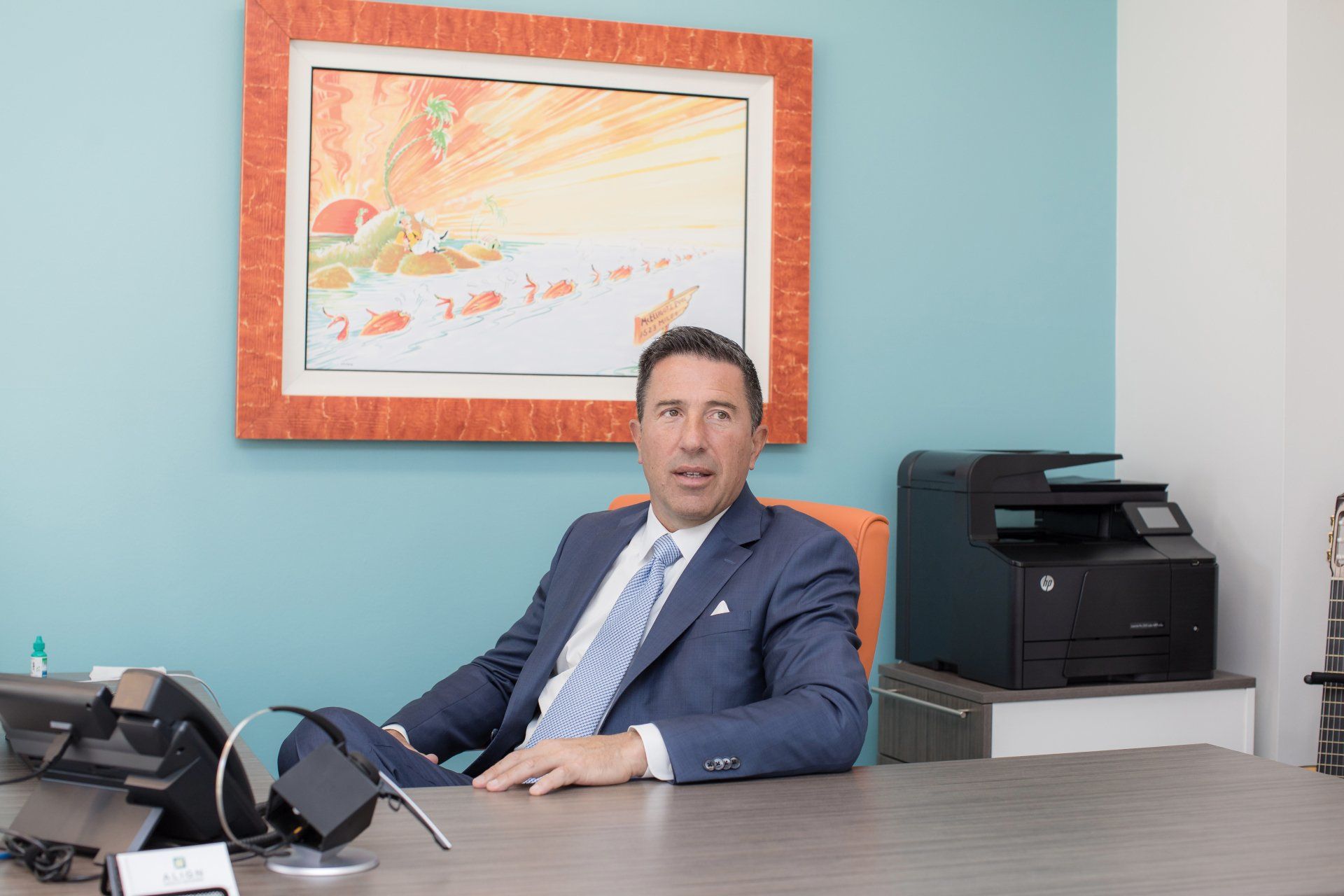 A man in a suit and tie is sitting at a desk in an office.