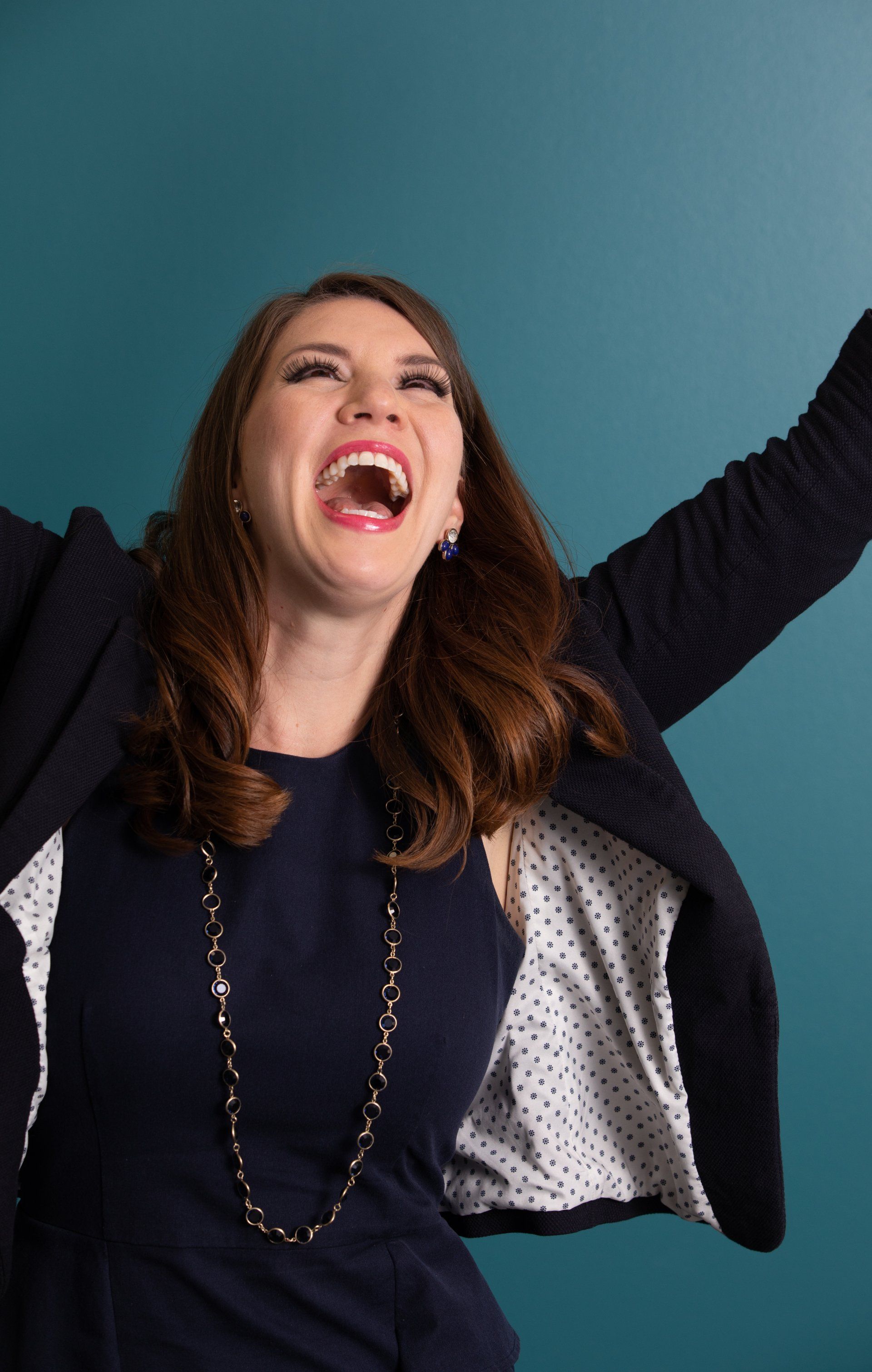 A woman is laughing with her arms in the air.