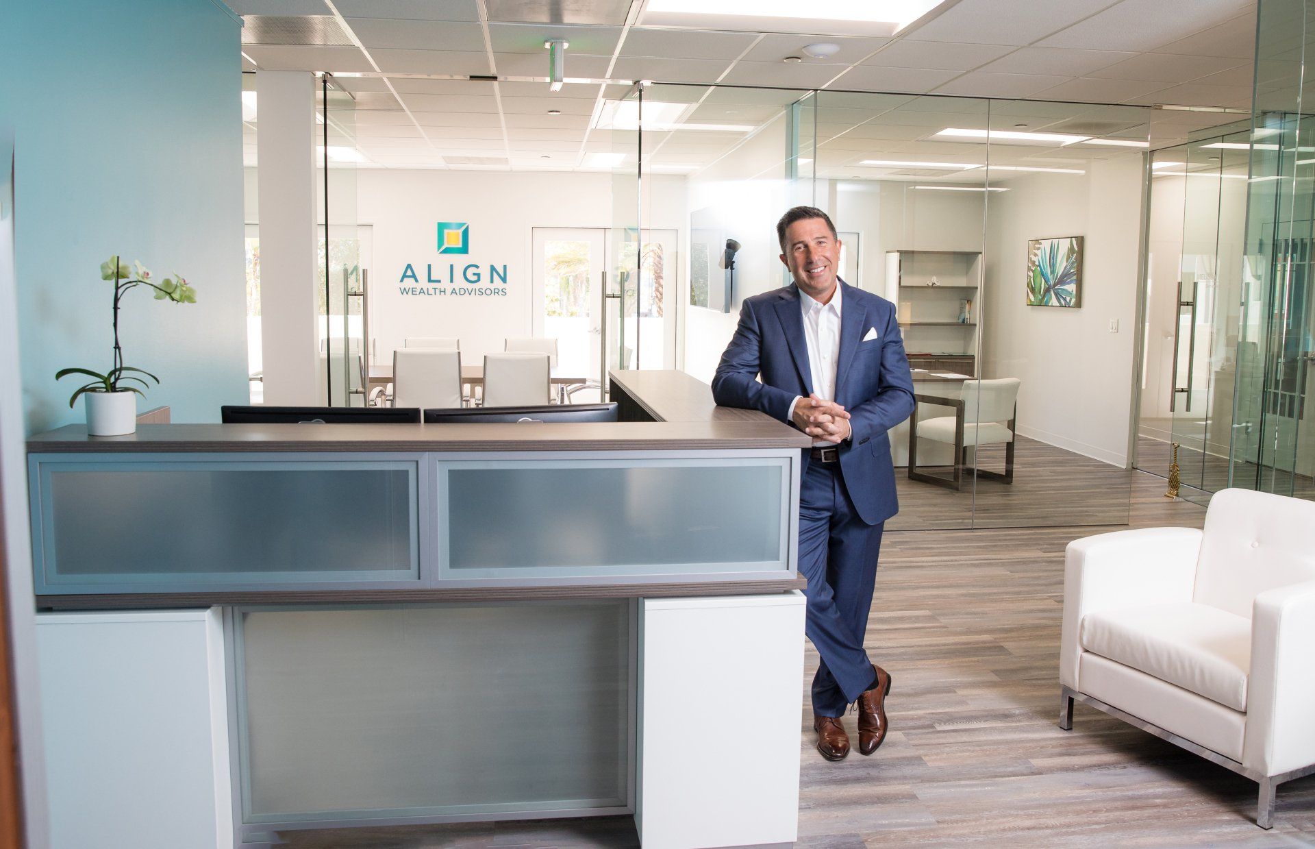 A man in a suit is standing in front of a reception desk in an office.