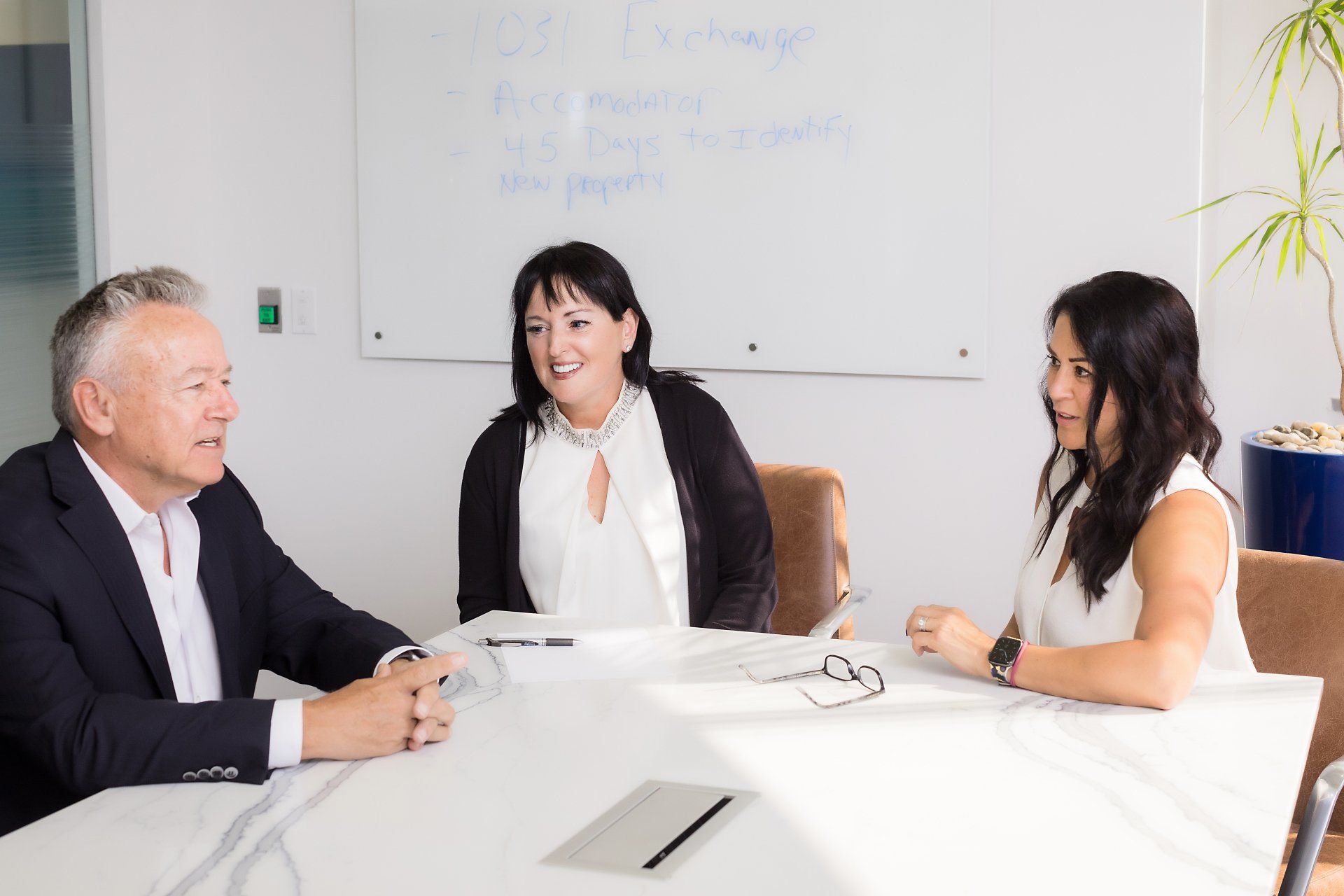 A man and two women are sitting at a table in a conference room.