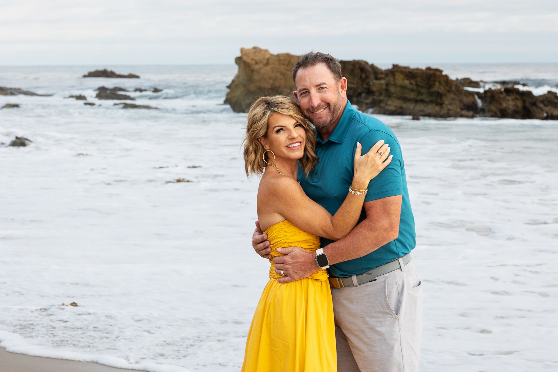 Mom and Dad posing in front of the ocean in Laguna Beach for a family portrait session.