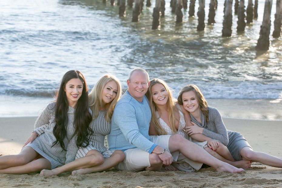 A family is posing for a picture on the beach.