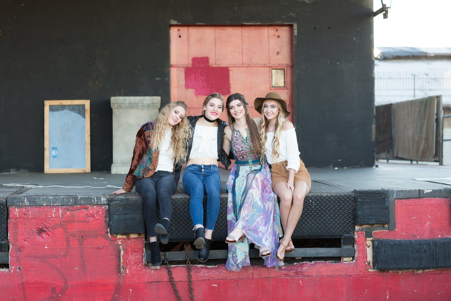 A group of young women are sitting on a red dock.