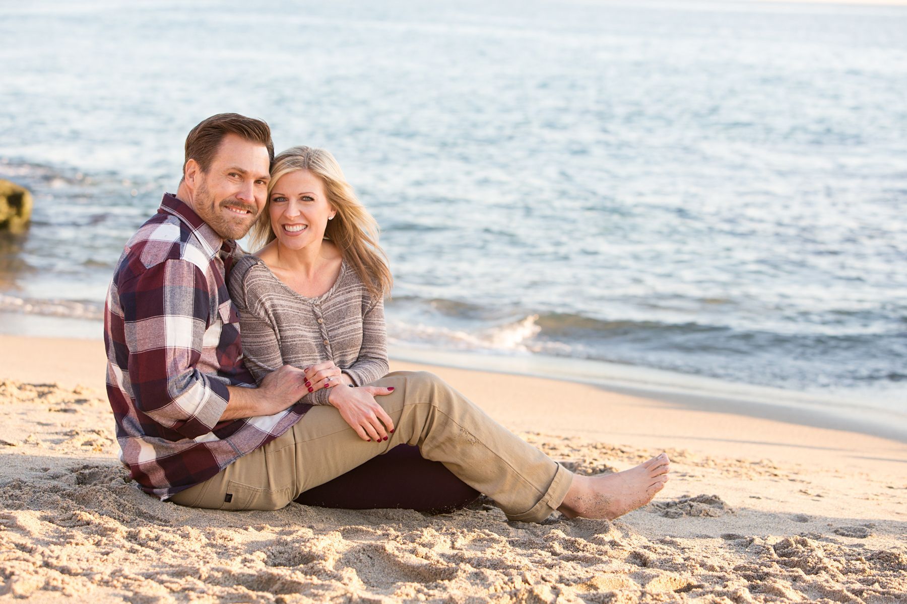 Mom and Dad snuggling on the beach for a family portrait.