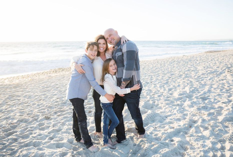 A family is posing for a picture on the beach.