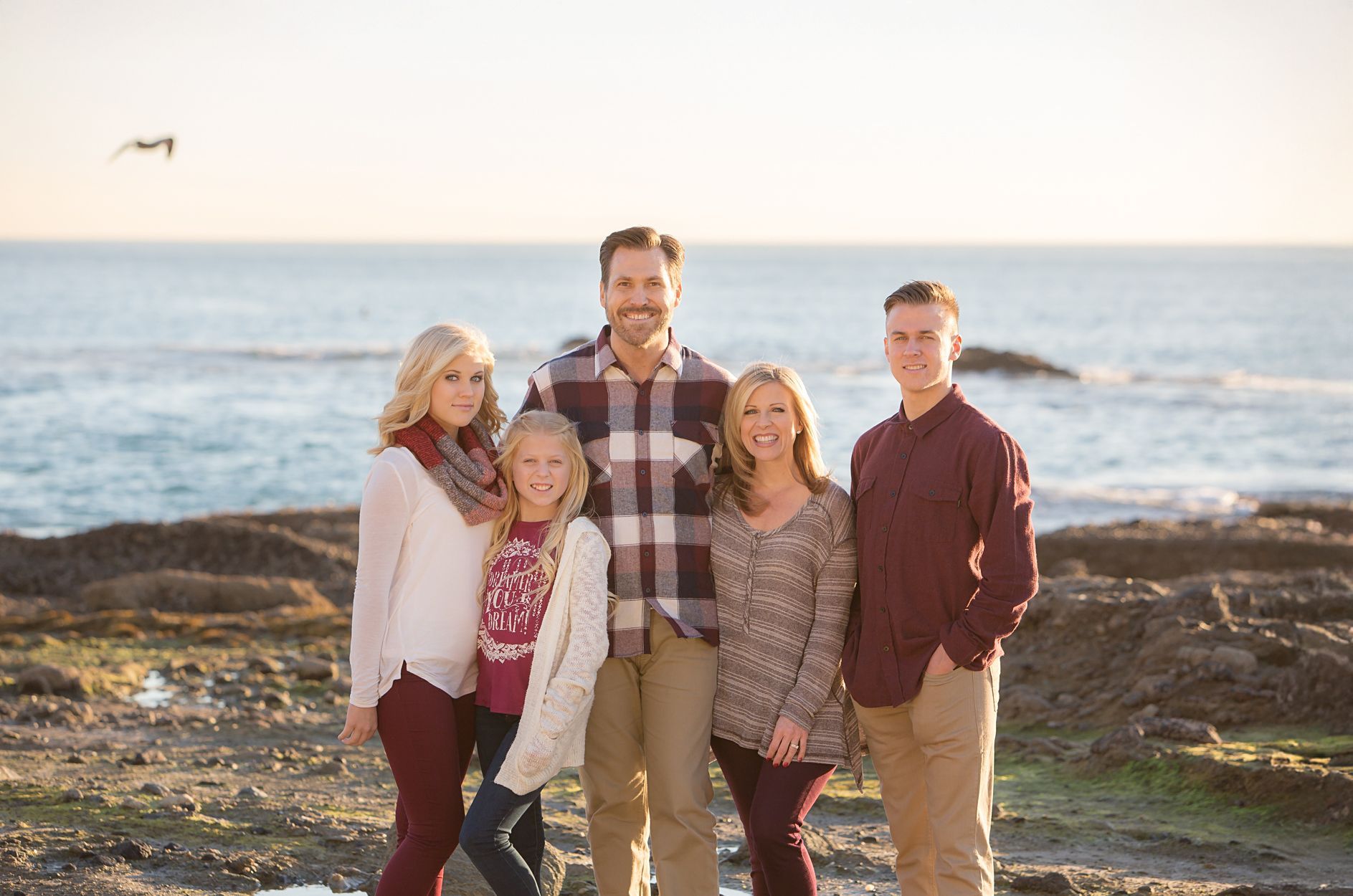 Family of 5 posing on the rocks at Victoria Beach during golden hour.