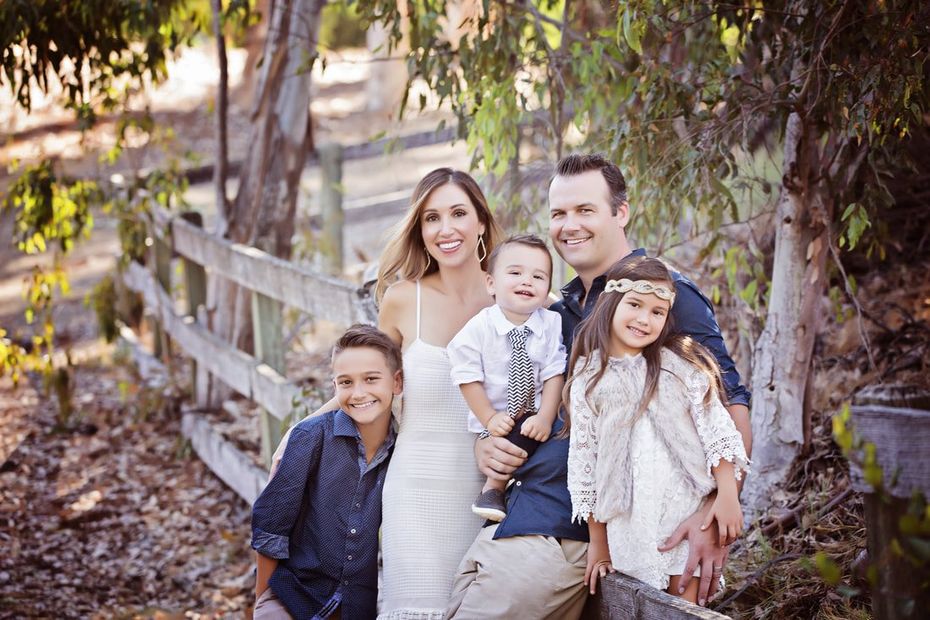 A family is posing for a picture in front of a wooden fence.