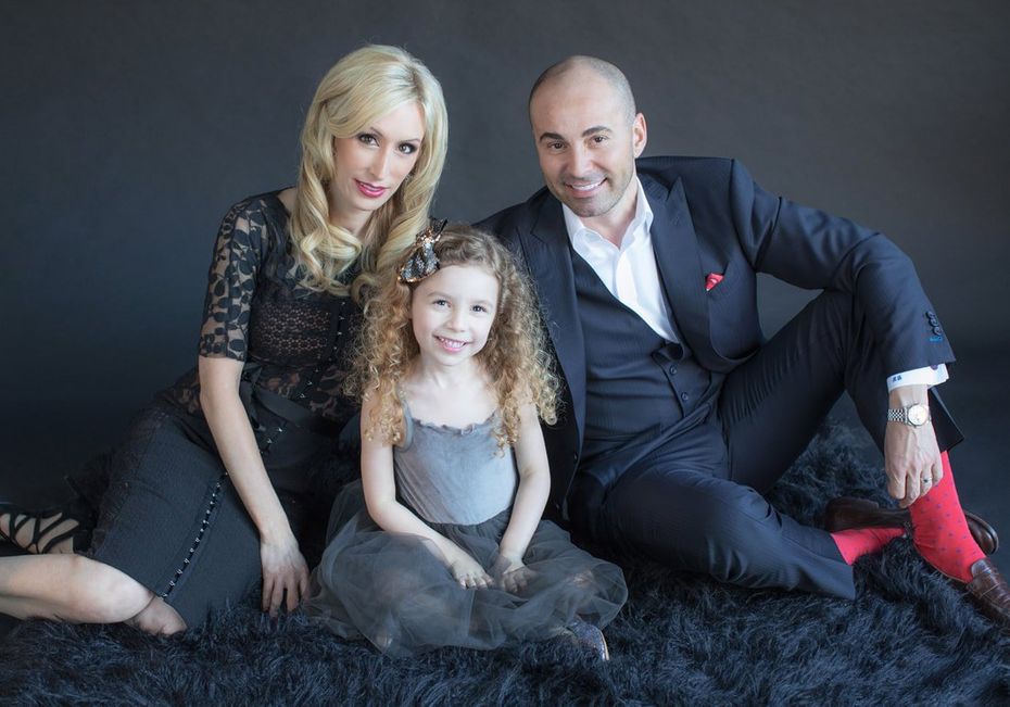 A family is posing for a picture while sitting on a black rug.