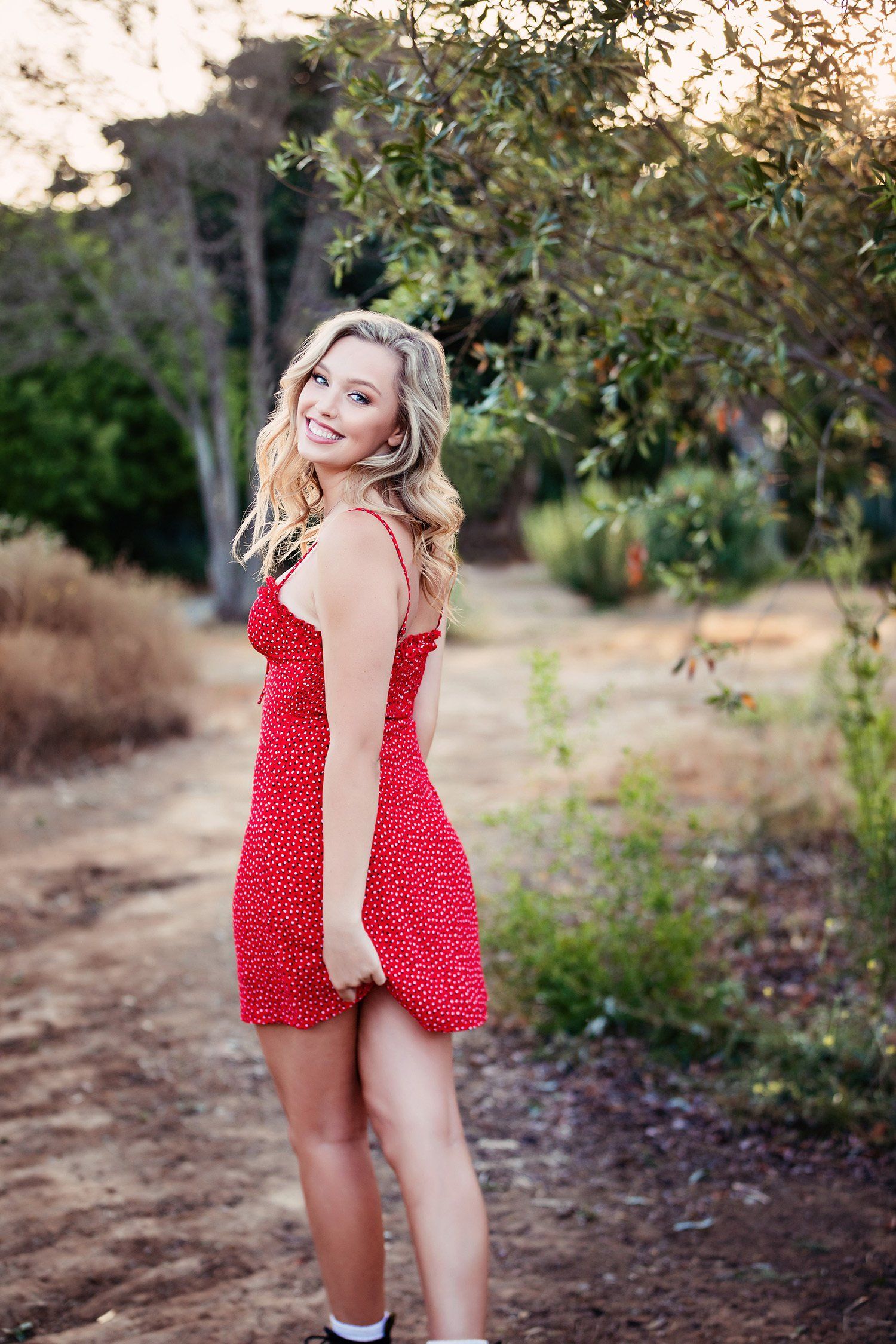A woman in a red dress is standing in a field.