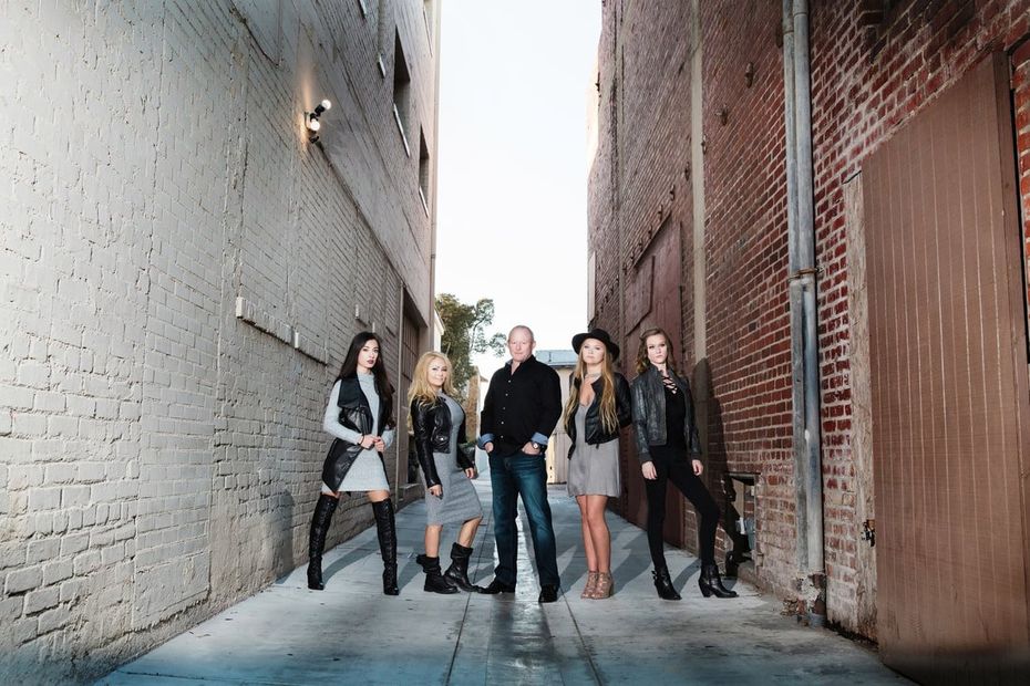 A group of people are standing in an alleyway between two brick buildings.