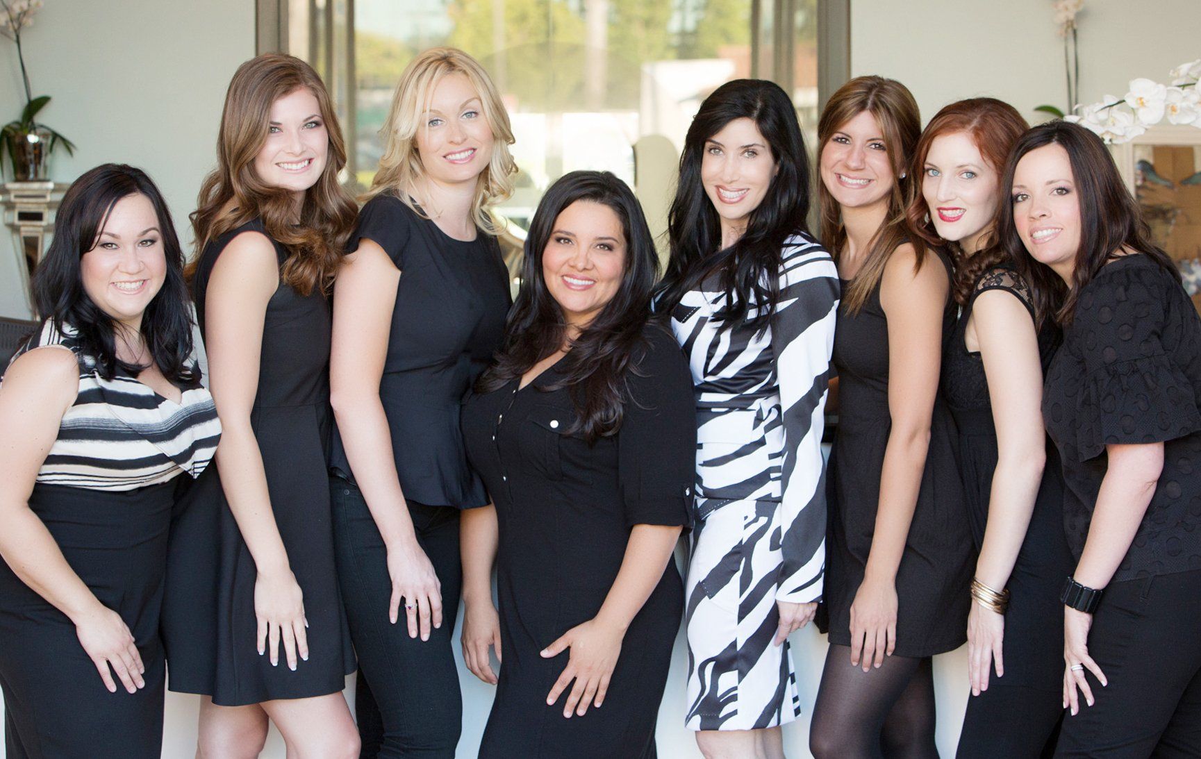 A group of women in black dresses are posing for a picture.