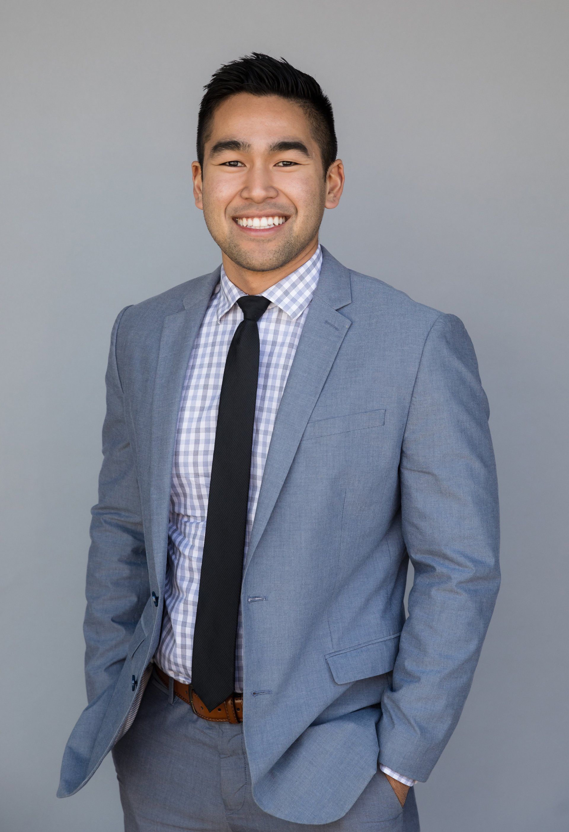 A man in a suit and tie is standing with his hands in his pockets.