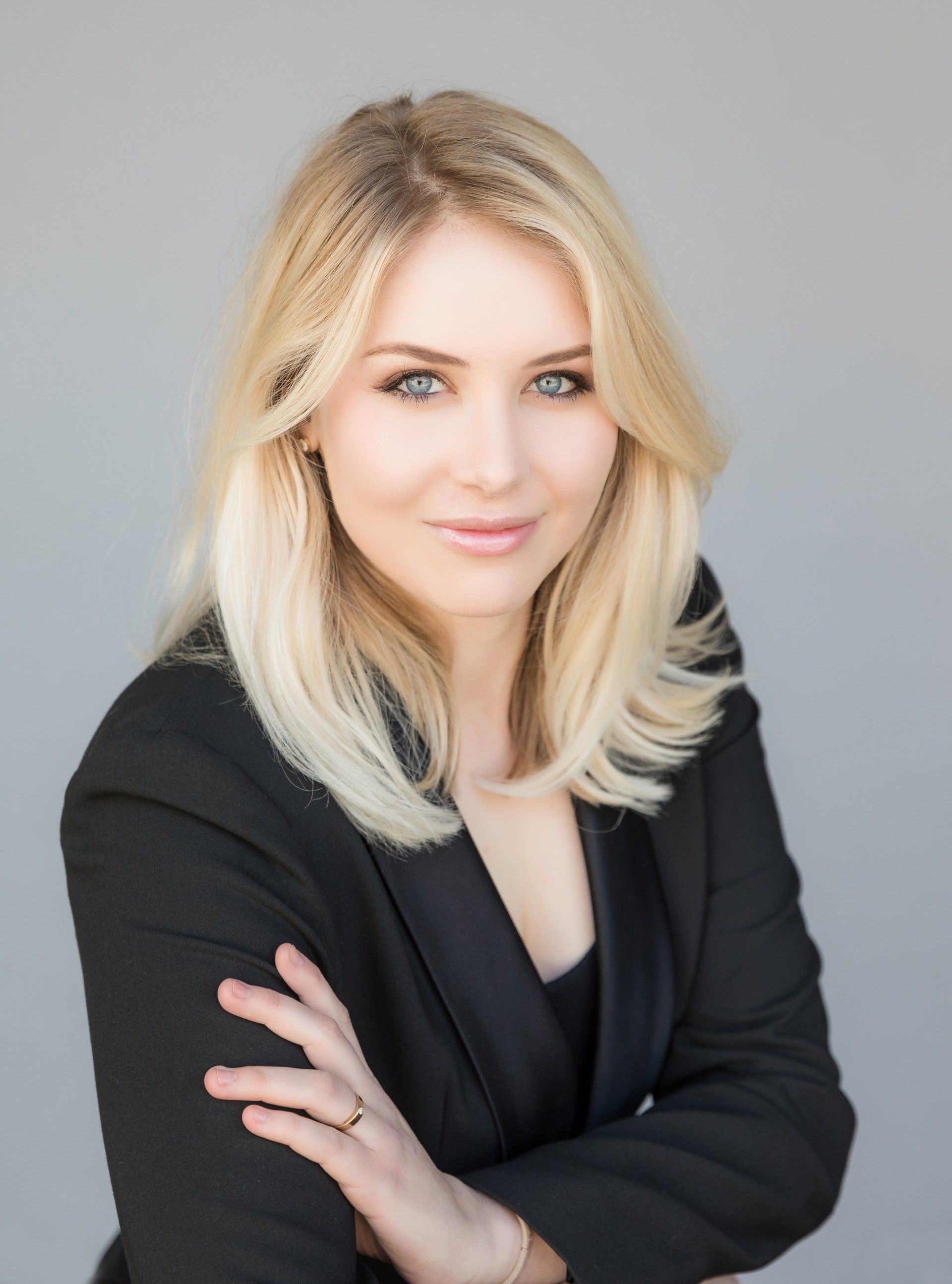 A woman in a black jacket is posing for a picture with her arms crossed.