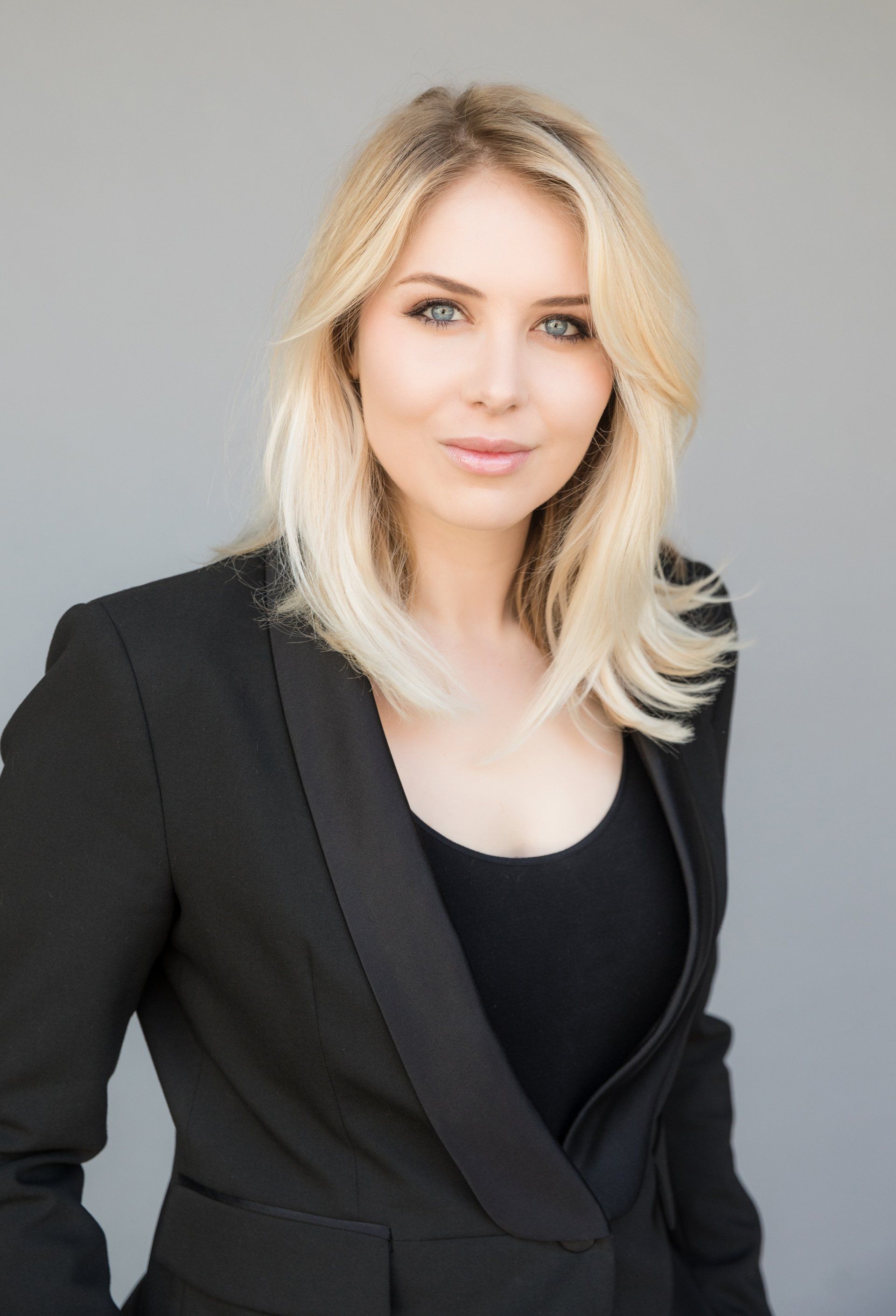 The woman is wearing a black jacket and a black tank top.