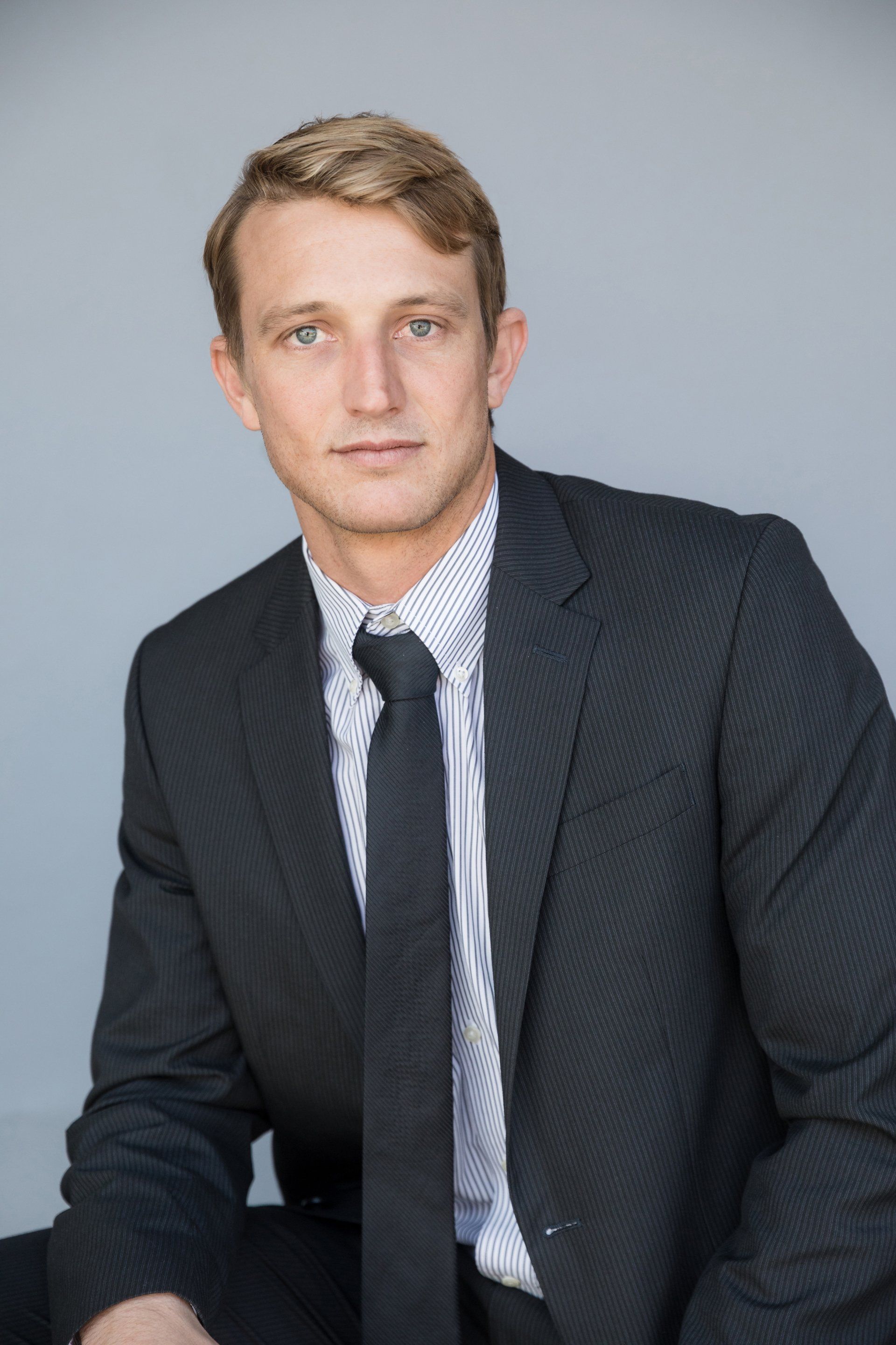 A man in a suit and tie is sitting down and looking at the camera.