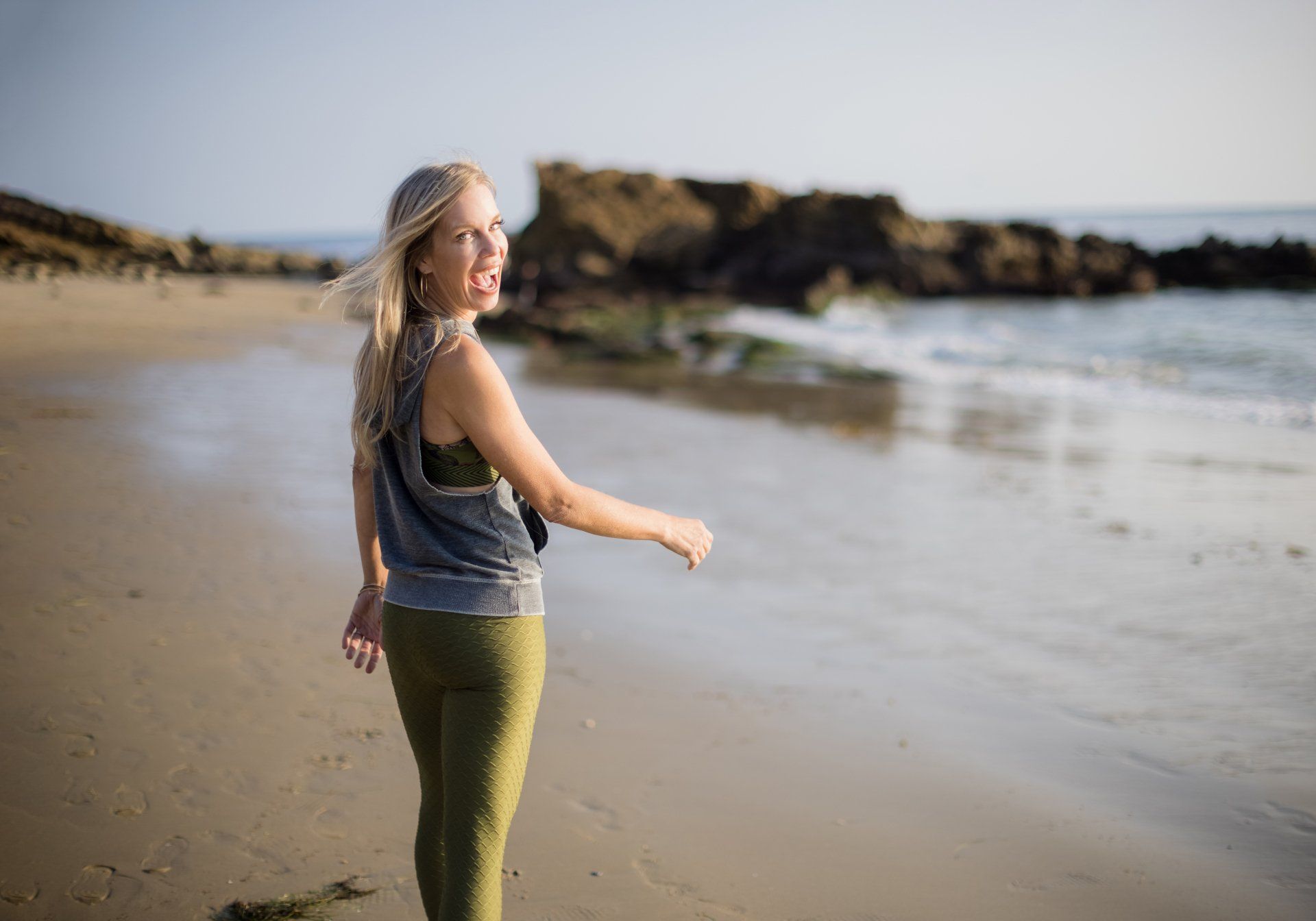 A woman is standing on a beach looking at the ocean.