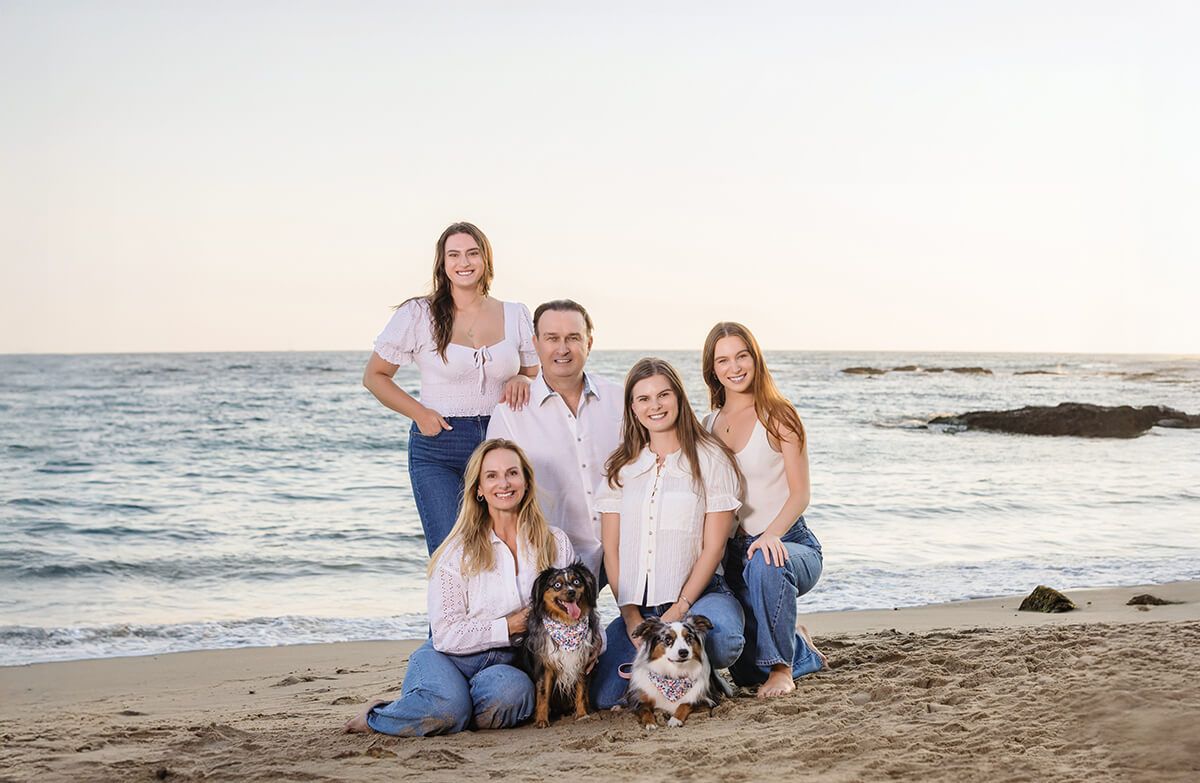 Sunset family beach portrait in Laguna Beach featuring parents, three daughters, and two dogs, captured by Orange County family photographer Blue Sky’s Studio.