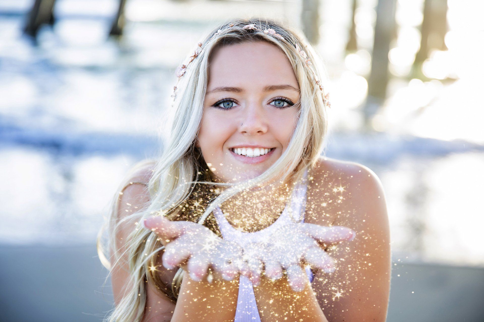 A woman is holding glitter in her hands and smiling.