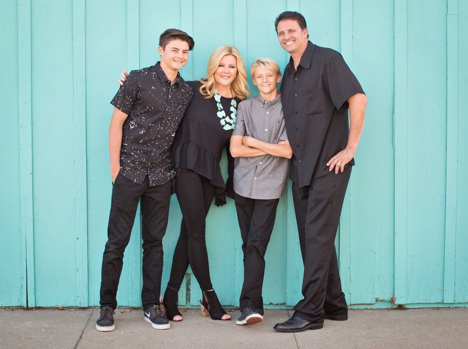 A family is posing for a picture in front of a blue wall.