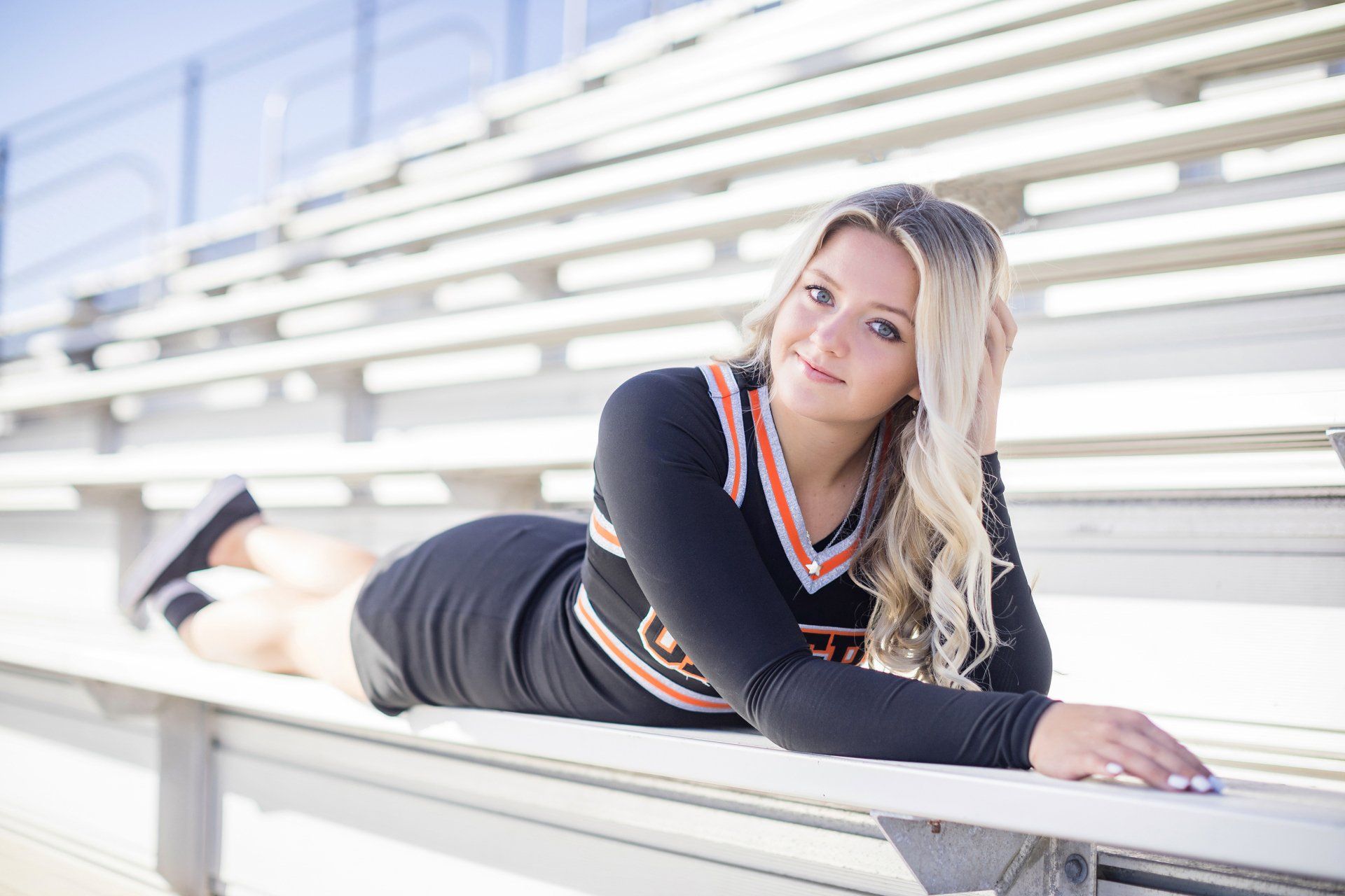 A cheerleader is laying on a bench in a stadium.